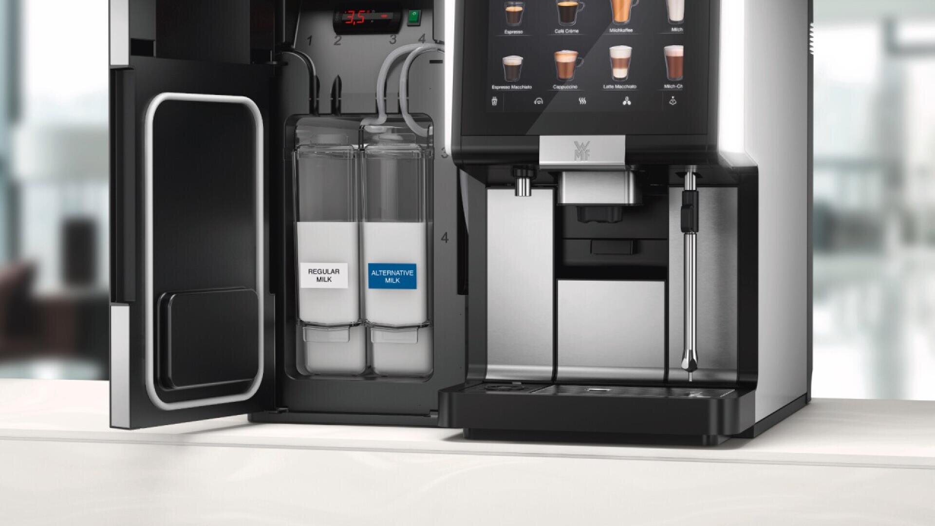 A modern coffee machine with its side door open, showing two labeled milk containers—one for regular milk and one for alternative milk—in a sleek, bright kitchen setting.