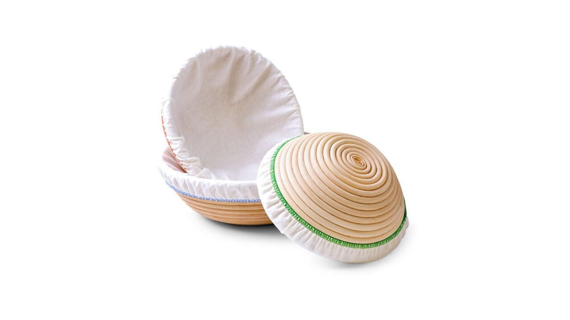 Two round proofing baskets with cloth liners, one upright and open, the other tilted on its side showing a spiral pattern and a green band around the edge, both set against a white background.