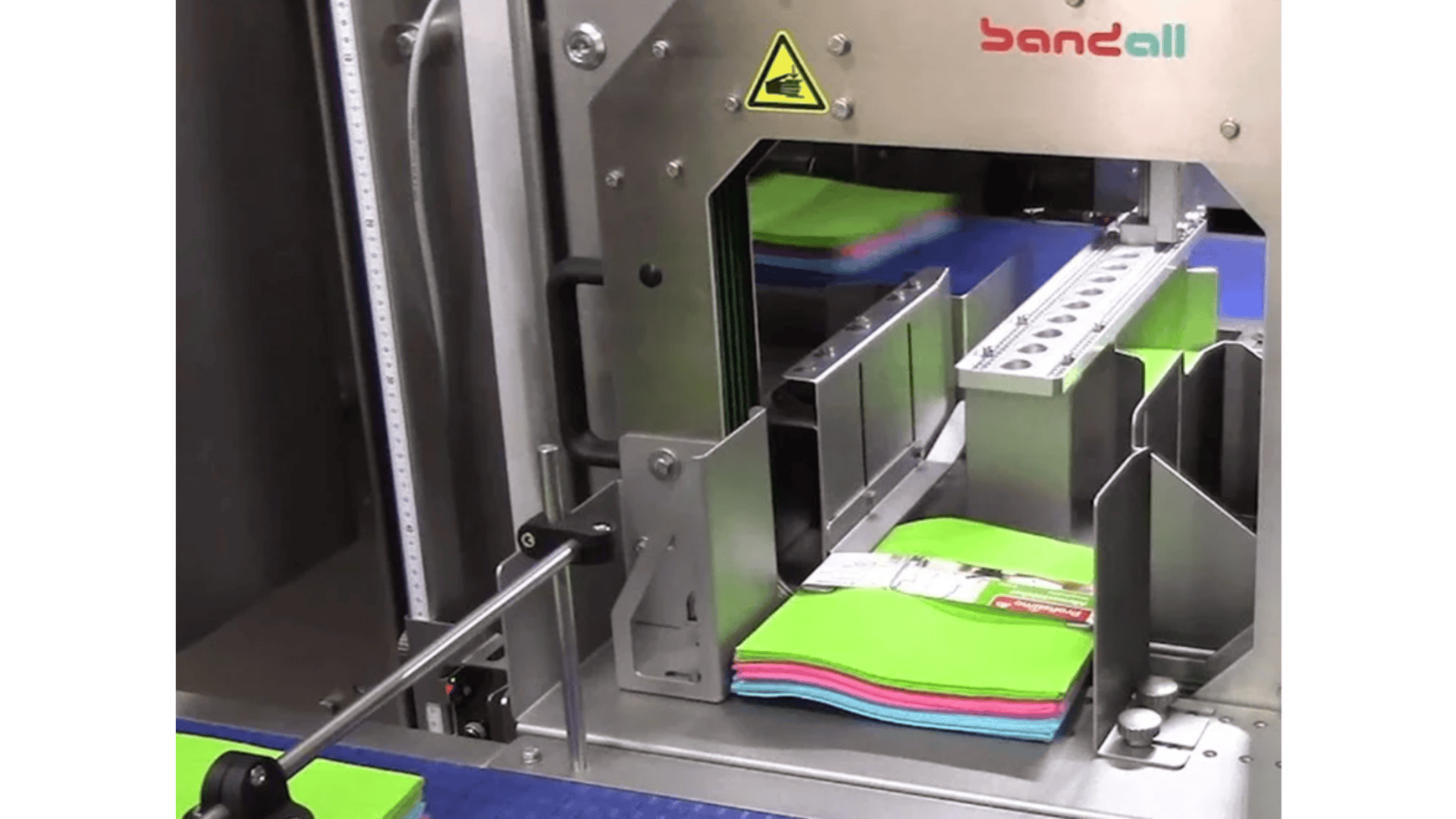 Ein Paket bunt gefalteter Tücher wird von einer automatischen Bandall-Banderoliermaschine in einer Industrieumgebung gebündelt.