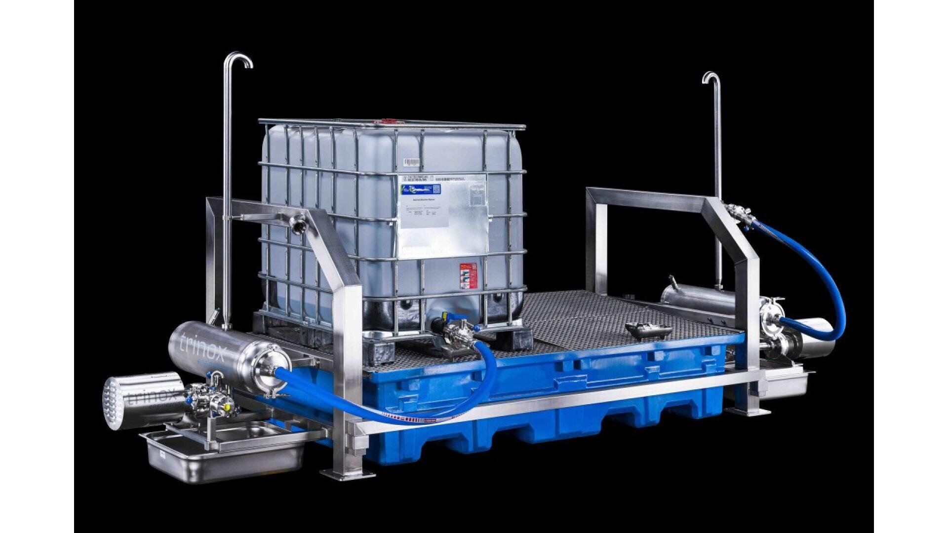 A large industrial liquid container sits on a blue spill containment platform, connected by blue hoses to stainless steel pumps and filters, all set against a black background.