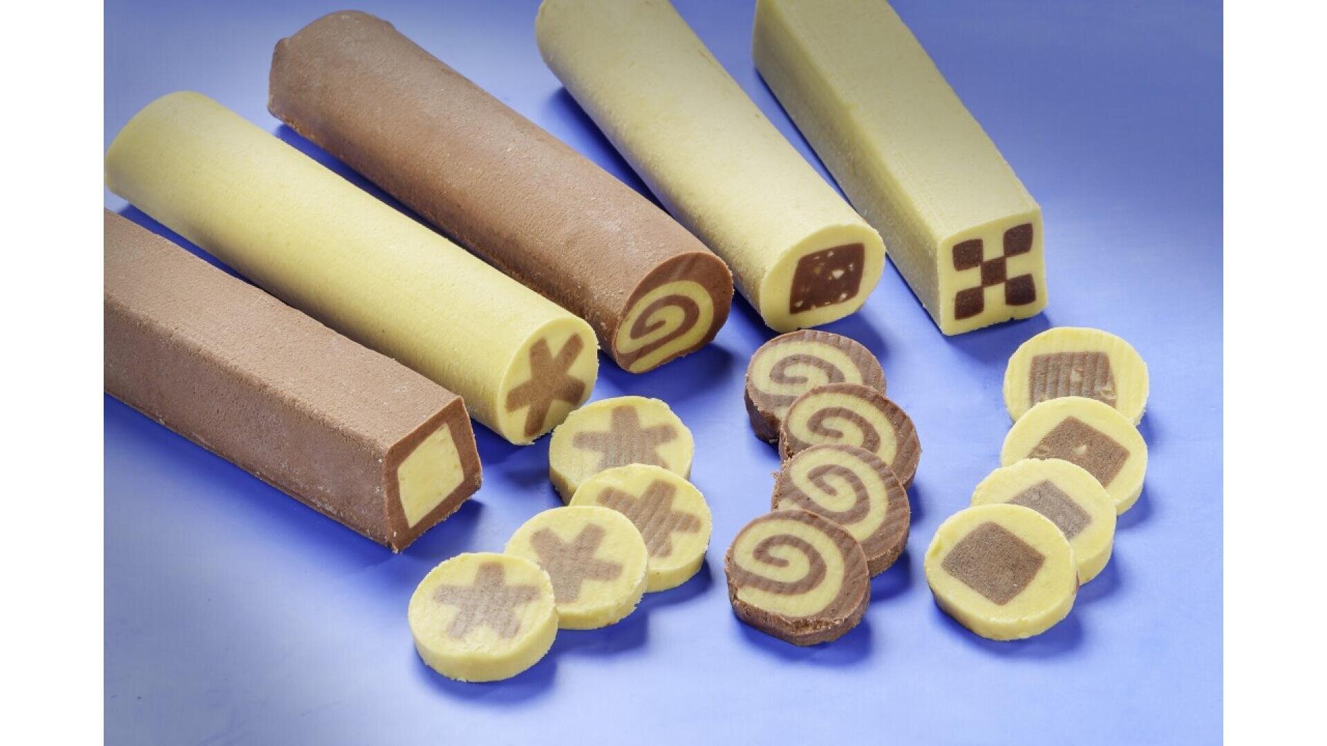 Four unbaked cookie dough logs with different patterns—cross, swirl, checkerboard, and square—are arranged above sliced cookies showing the same patterns, all on a light blue surface.