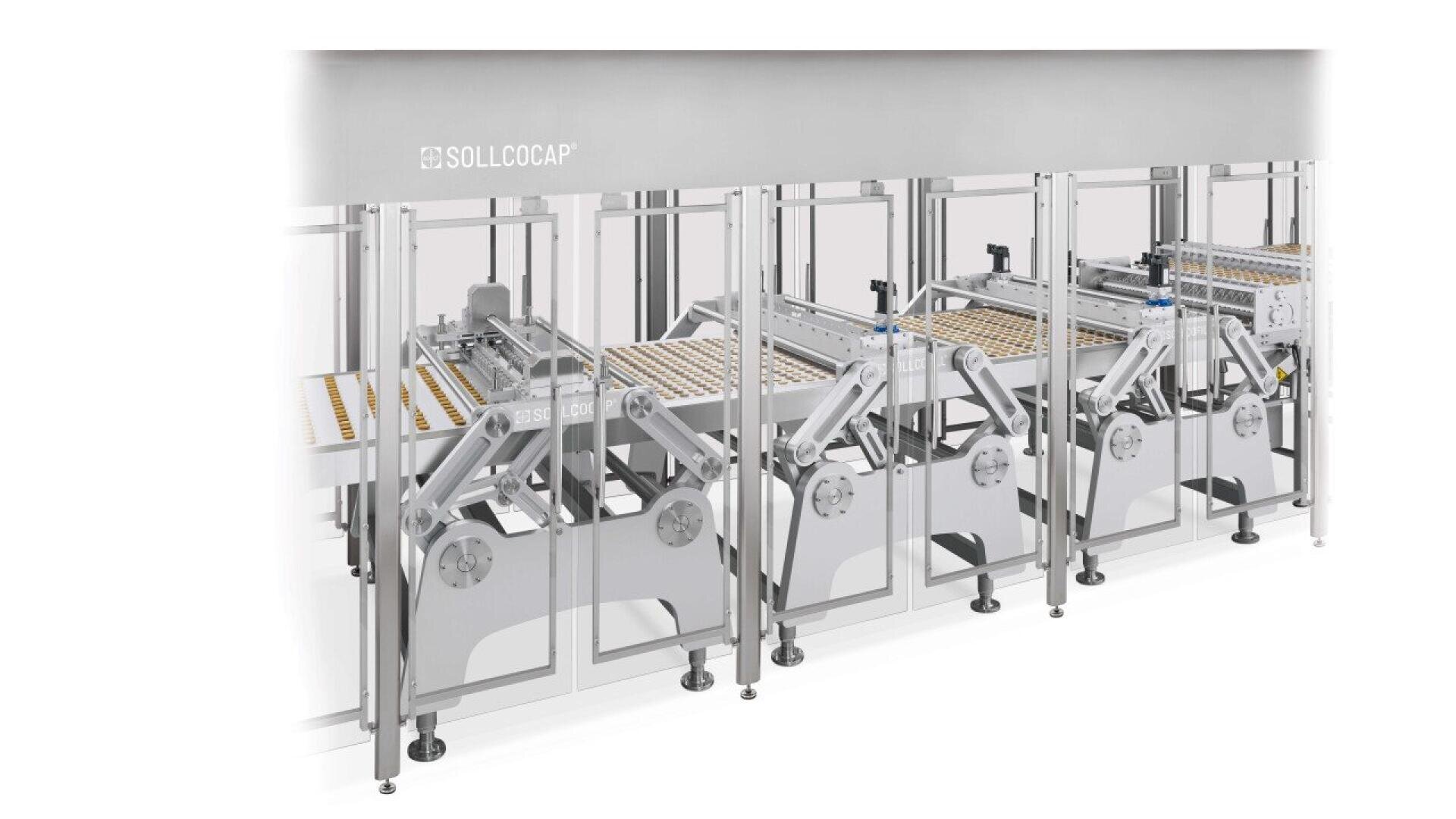 Automated industrial machine with metal arms and conveyor belts processing small round items, enclosed in a glass and metal safety structure, branded with the name SOLLOCAP.