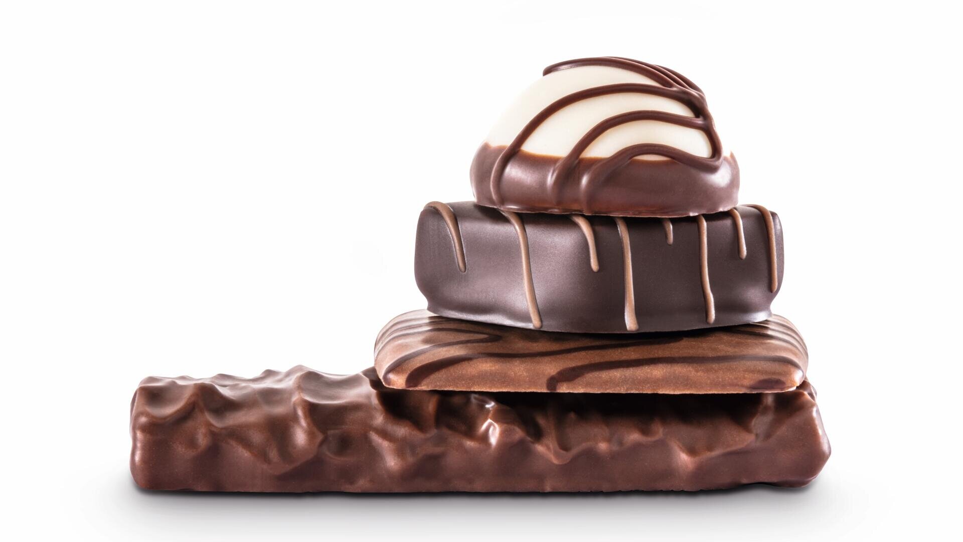 Ein Stapel von vier verschiedenen Schokoladenbonbons, jedes mit einer anderen Form und einem anderen Streumuster, angeordnet vom größten zum kleinsten auf einem weißen Hintergrund.