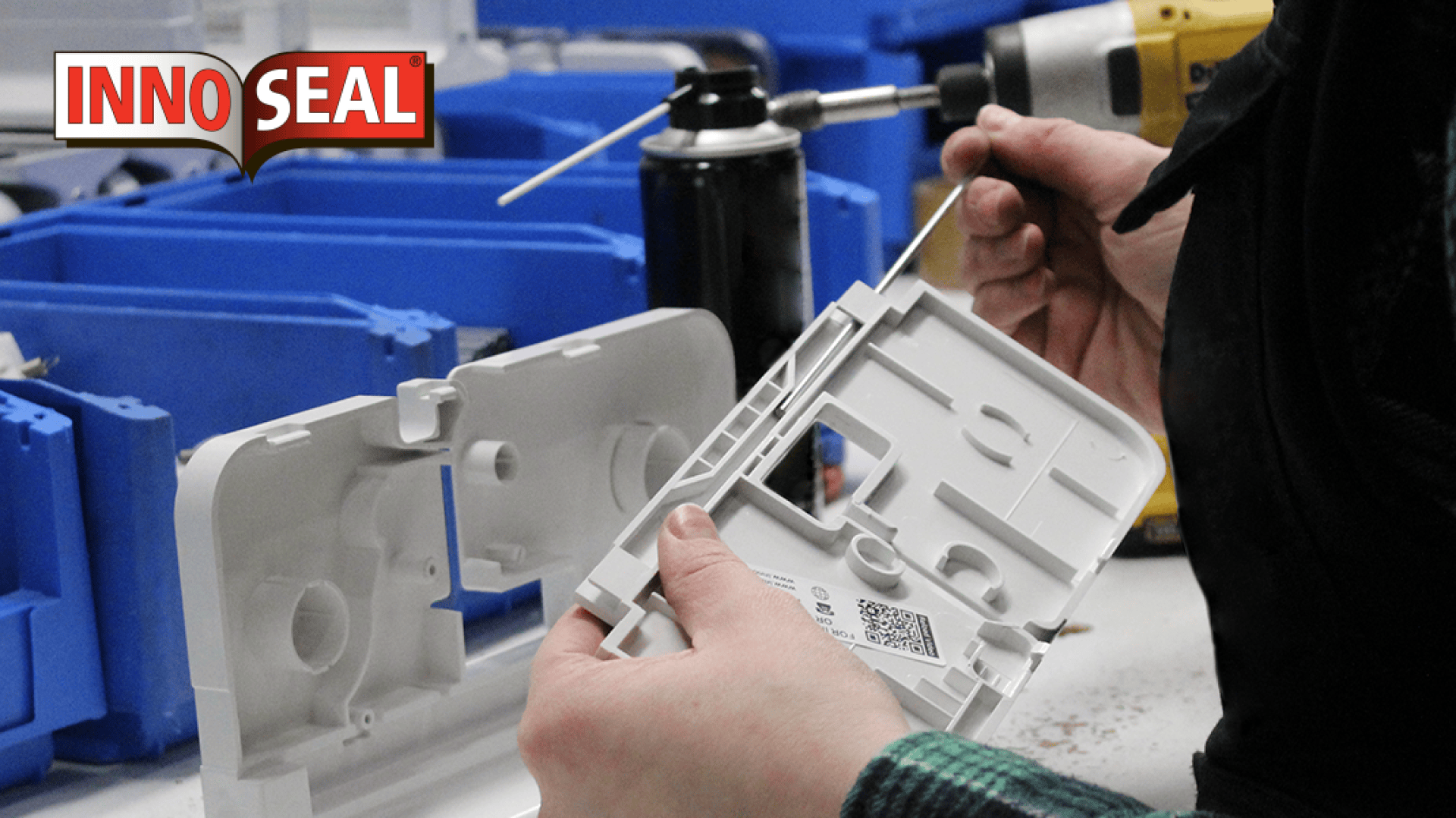 A person cleans a white plastic component with a cotton swab at a workstation with blue bins and tools. A can of spray and a drill are visible. The INNOSEAL logo appears in the top left corner.