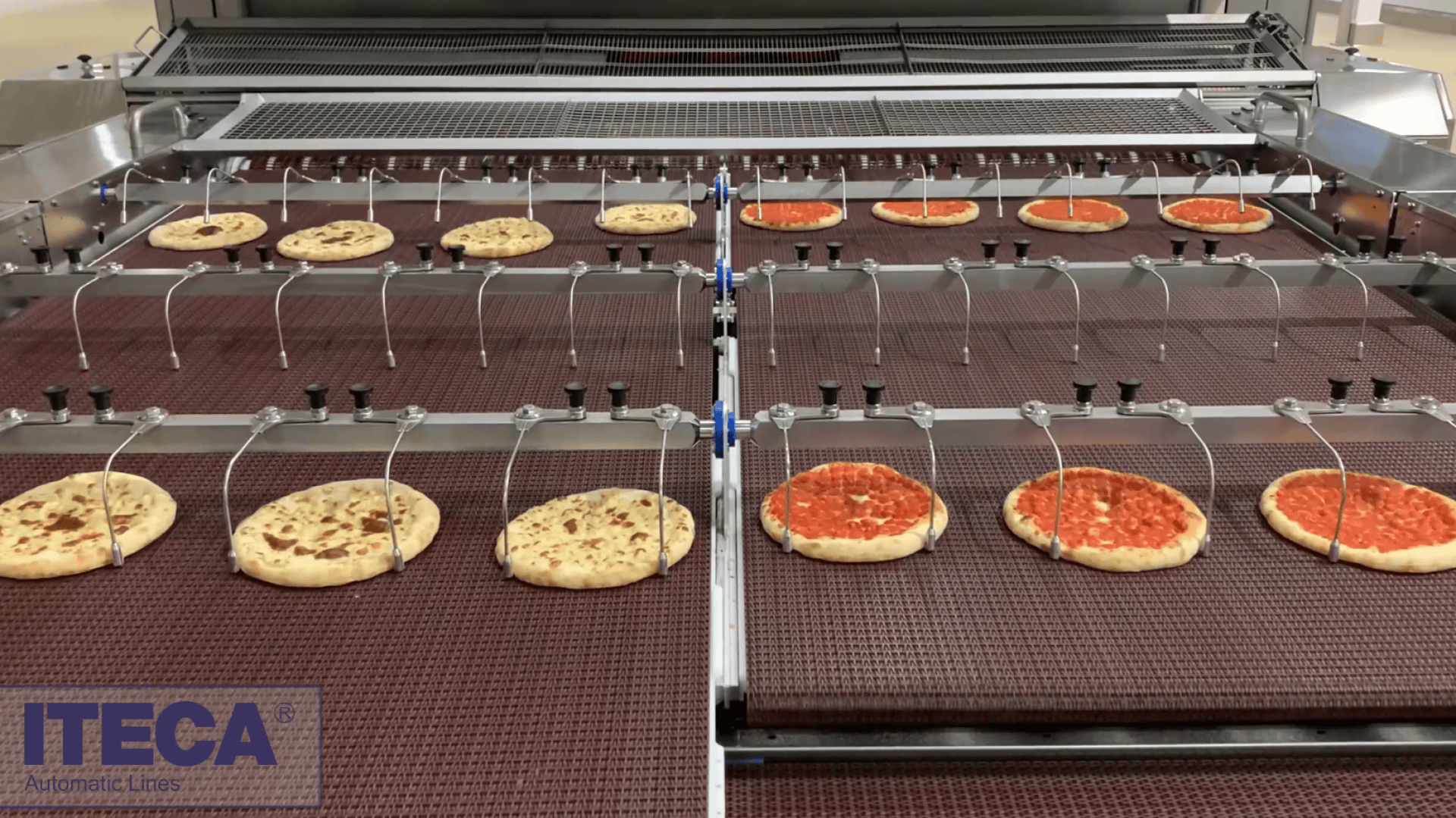 Pizzas move along an automated conveyor belt in a food production facility. Toppings are being added by machinery above the pizzas. The company name “ITECA” is visible in the bottom left corner.