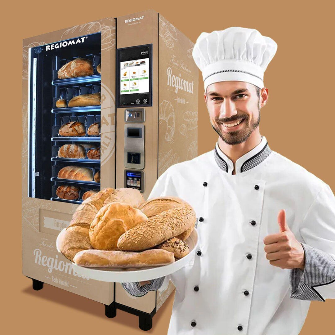 Ein lächelnder Bäcker in weißer Uniform und Kochmütze hält einen Teller mit verschiedenen Brotsorten vor einem Brotautomaten und streckt den Daumen hoch. Der Hintergrund ist hellbraun.