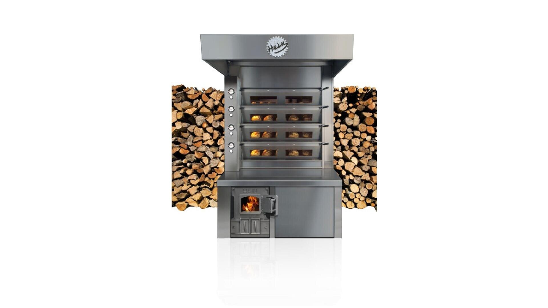 A modern, stainless steel wood-fired oven with stacked firewood on both sides. The oven has six glass-fronted baking chambers and a fire burning in the lower compartment.