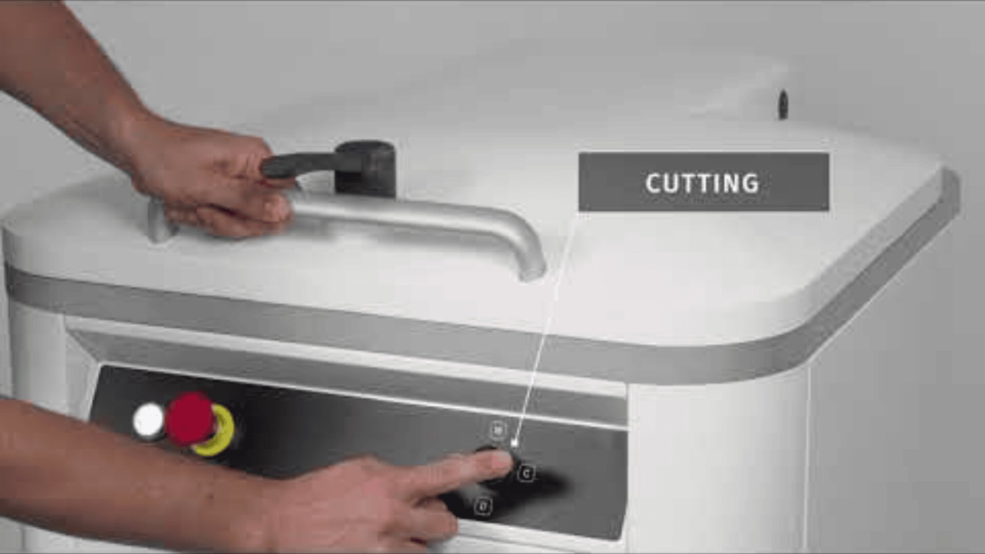 Eine Person drückt Tasten auf dem Bedienfeld einer großen weißen Maschine, während sie deren Griff festhält. Ein Schild mit der Aufschrift CUTTING zeigt auf das Bedienfeld. Das Bedienfeld ist mit einem gelb-roten Not-Aus-Knopf versehen.