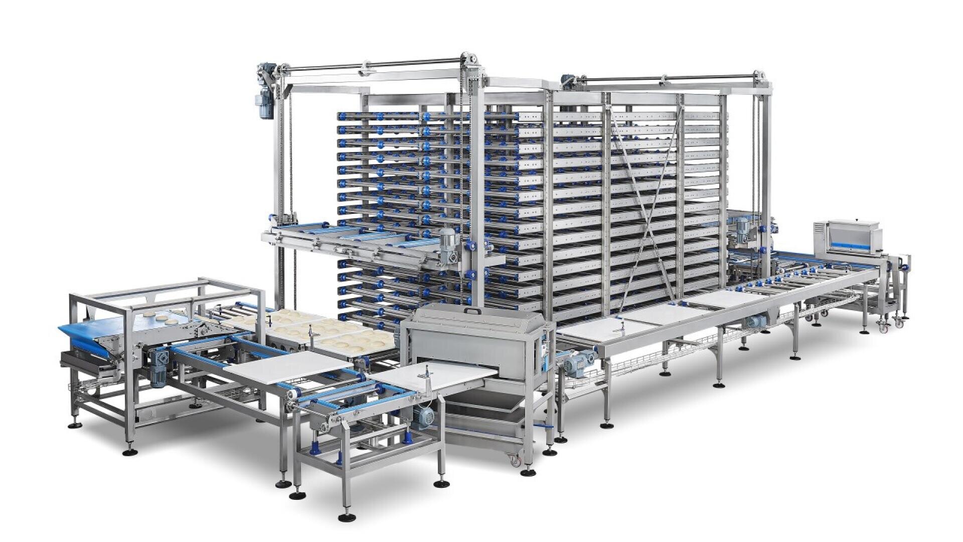 Automated industrial baking equipment featuring multiple conveyor belts, stacked racks, trays, and metal frameworks, designed for large-scale food production and processing in a factory setting.