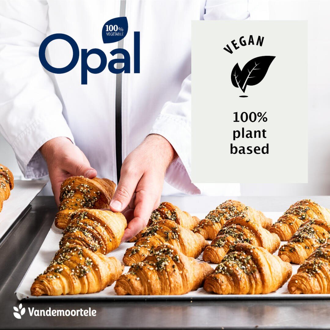 A person in a white coat arranges trays of golden, seeded croissants. Text reads Opal, Vegan 100% plant based, and Vandemoortele. Image promotes vegan croissants.