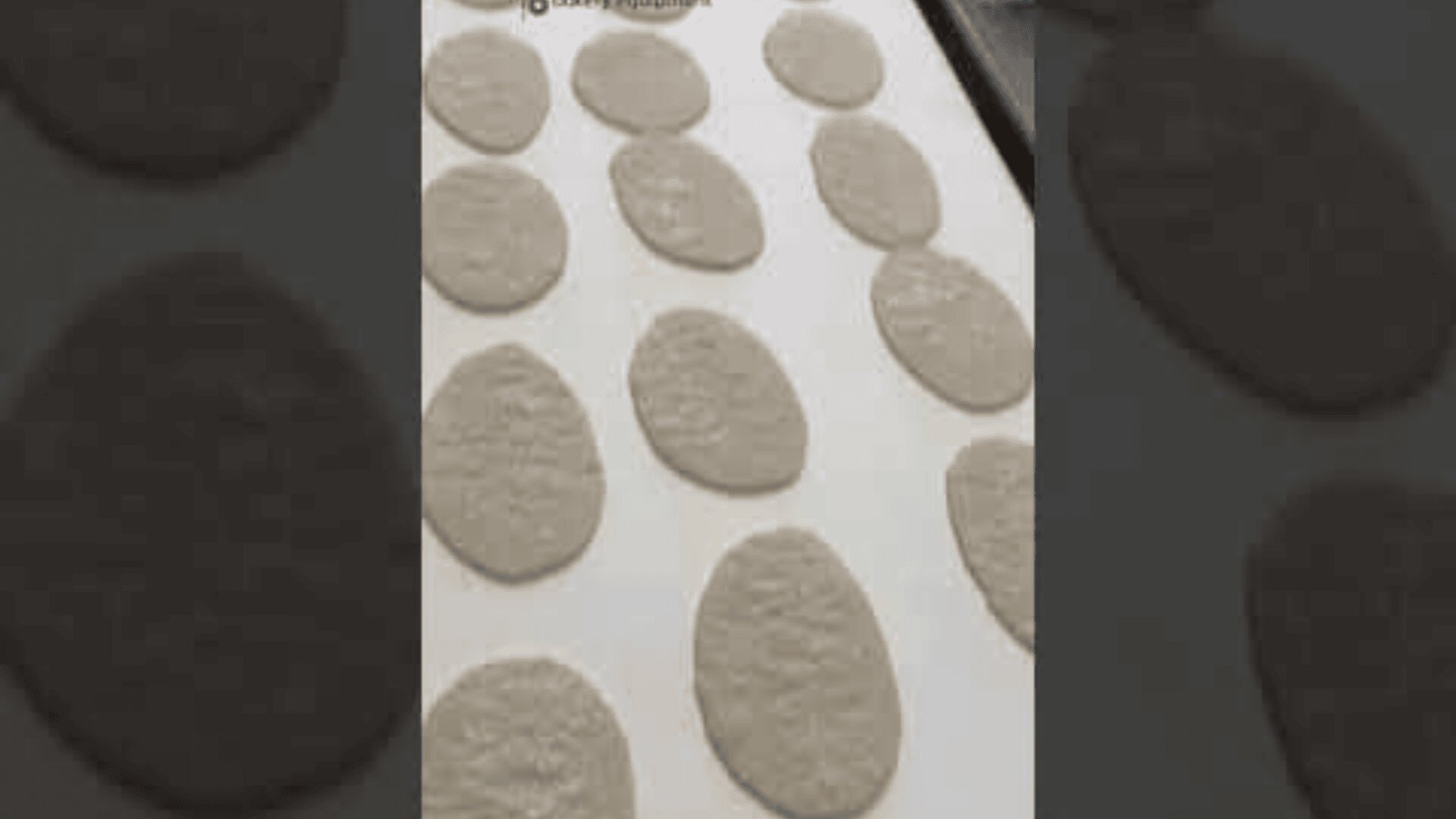 Mehrere ovale Teigstücke werden in Reihen auf einem mit Pergamentpapier ausgelegten Backblech angeordnet und sind bereit zum Backen.