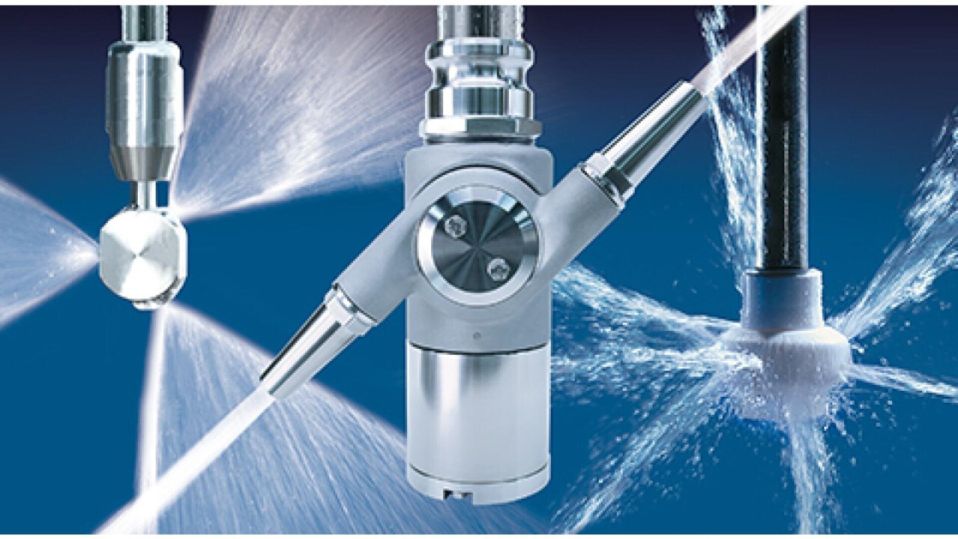 Close-up of three industrial spray nozzles expelling powerful streams and sprays of liquid in different directions, set against a blue background. The nozzles are metallic and designed for high-pressure cleaning.