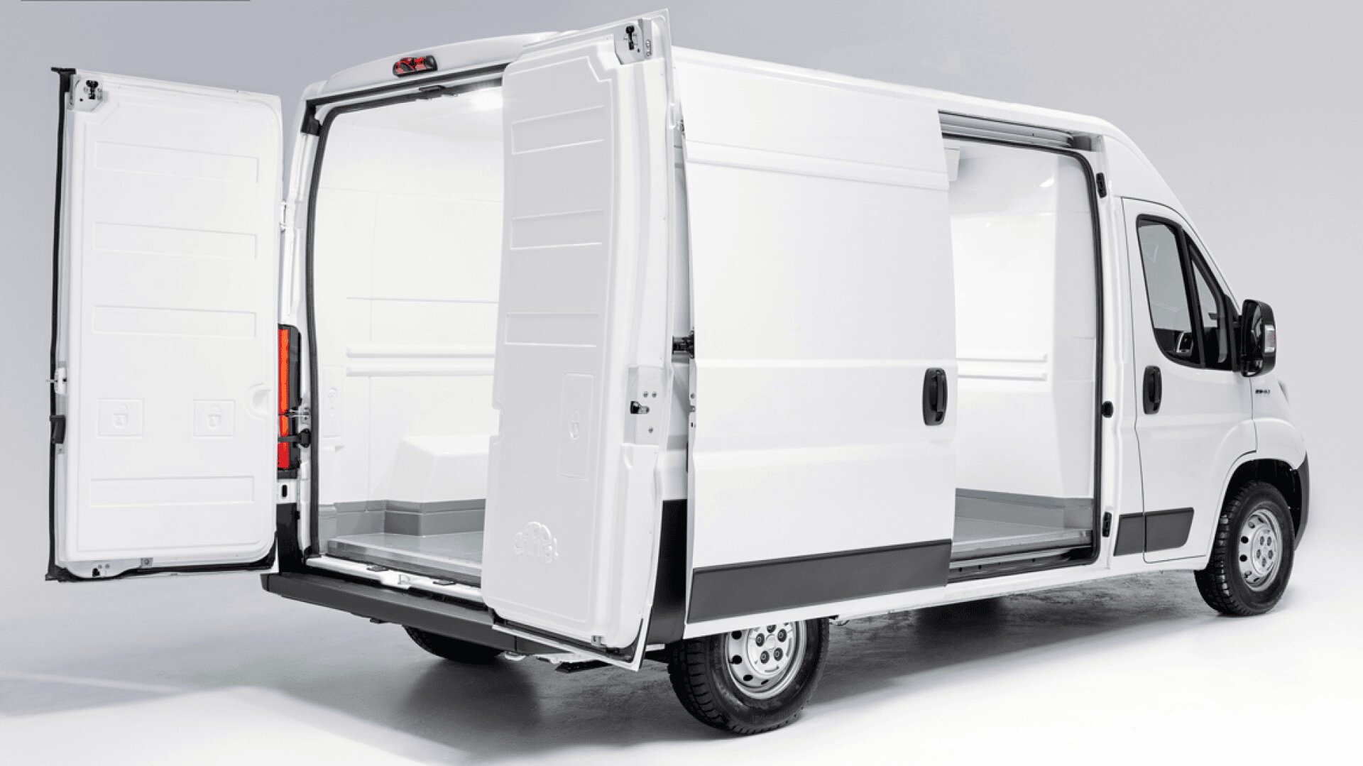 Ein weißer Transporter, dessen Heck- und Seitentüren geöffnet sind und einen leeren, sauberen Innenraum mit glatten weißen Wänden und Böden für den Transport von Waren offenbaren. Der Transporter ist in einem gut beleuchteten Studio geparkt.