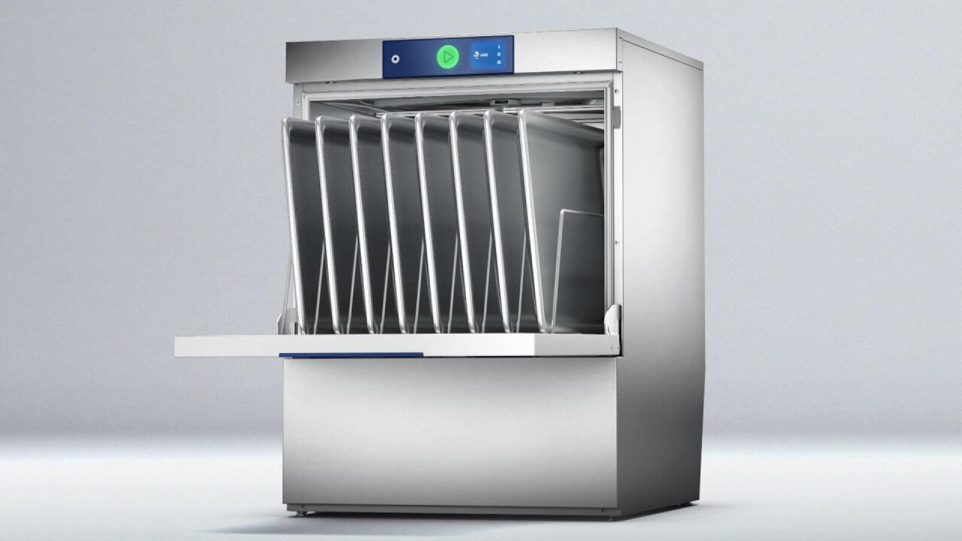 A commercial dishwasher with an open door displays several metal trays arranged upright inside, ready for washing. The machine has a stainless steel exterior and a simple control panel at the top.