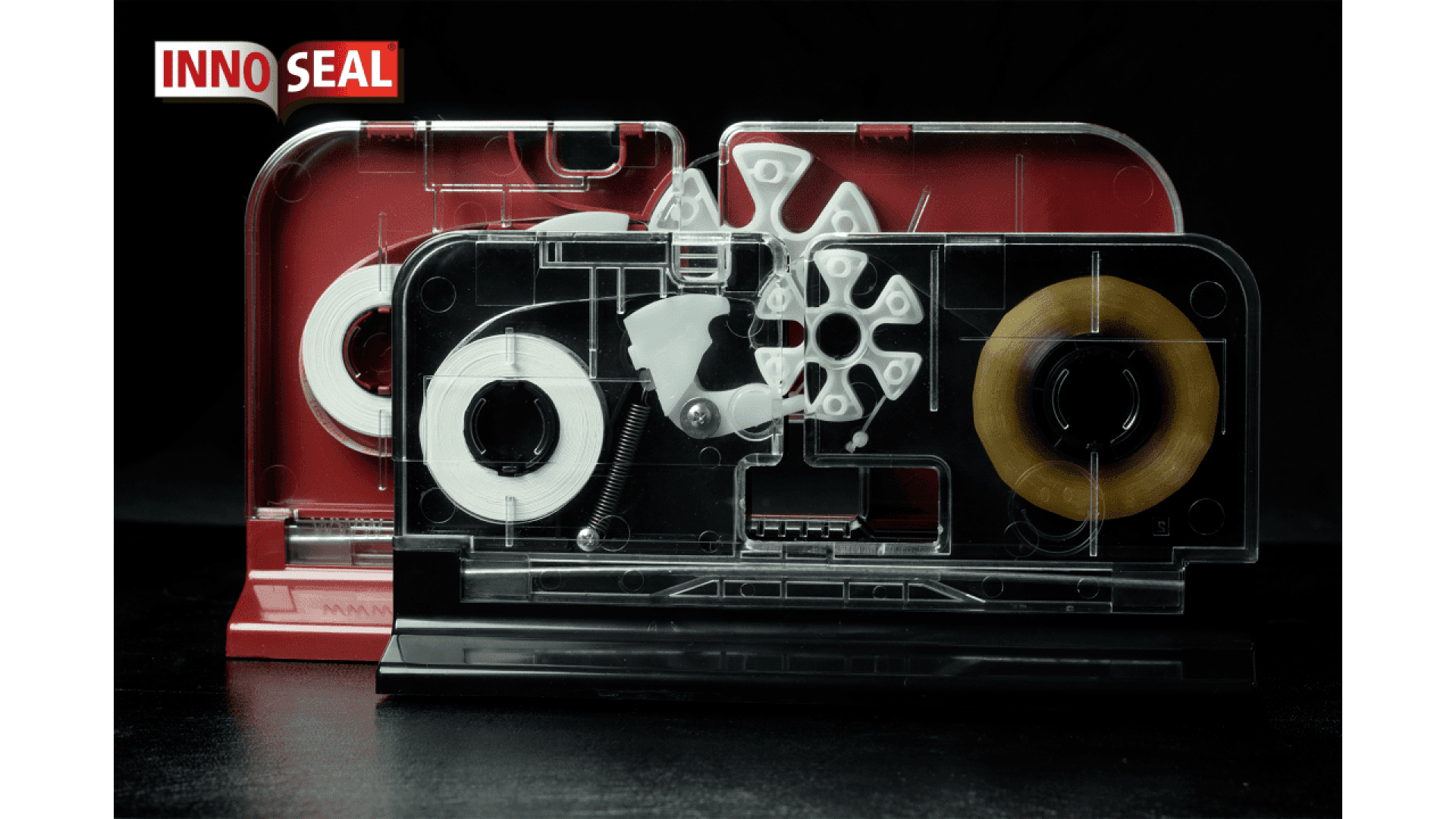 Zwei transparente Klebebandkassetten, eine mit weißem und die andere mit braunem Klebeband, sind nebeneinander vor einem schwarzen Hintergrund angeordnet. Das INNO SEAL-Logo ist in der oberen linken Ecke zu sehen.