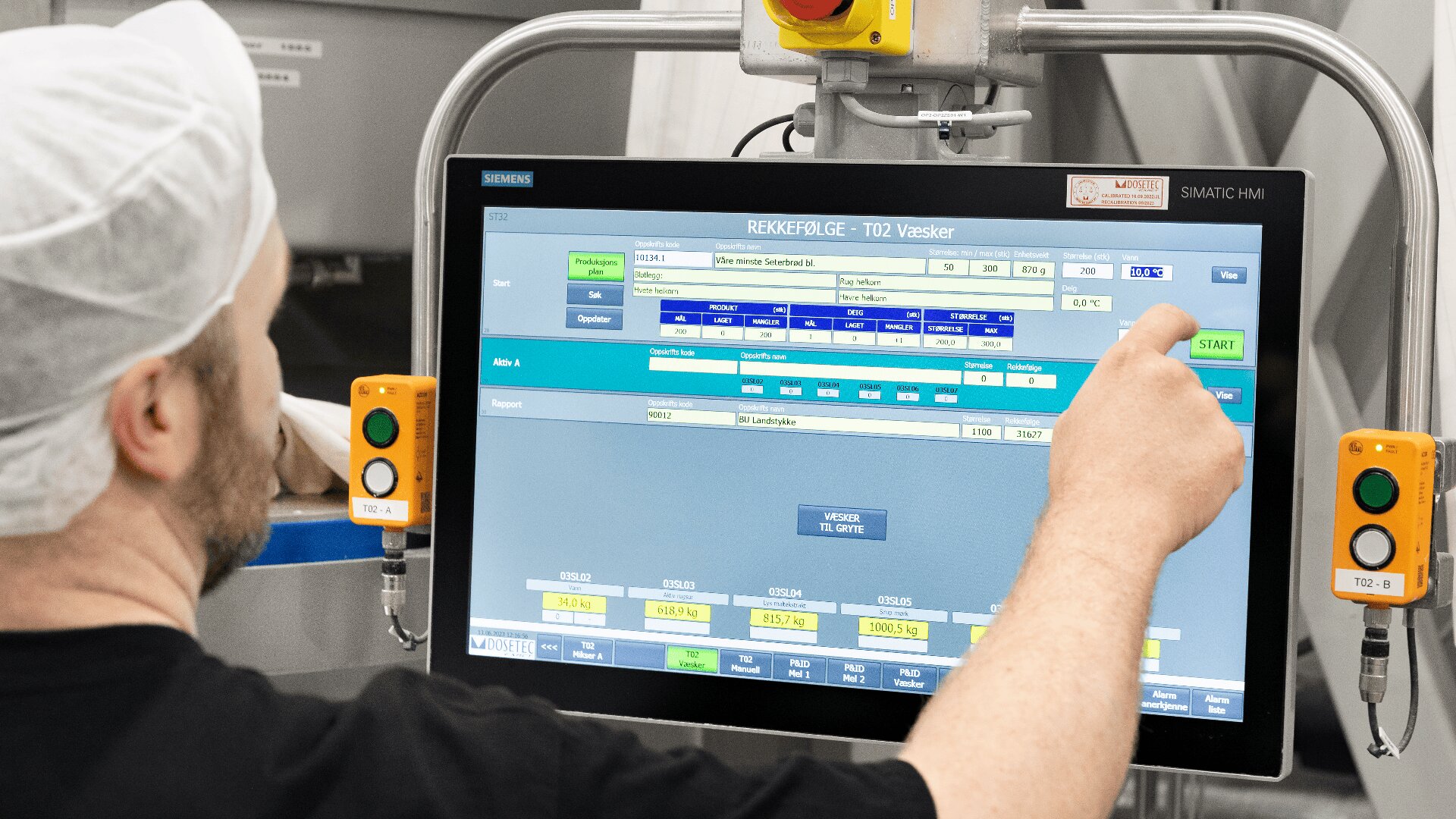 A person wearing a hairnet and black shirt operates a touchscreen control panel with various buttons and data displays in an industrial or laboratory setting.