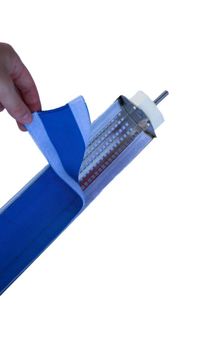 Eine Hand hebt eine blaue Stoffhülle mit Klettverschluss an und gibt den Blick frei auf einen LED-Lichtstreifen, der an einem Metallstab vor einem weißen Hintergrund befestigt ist.