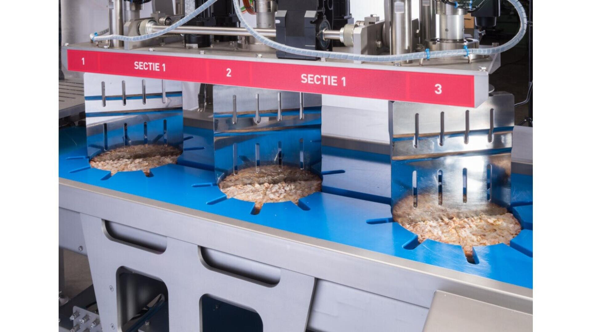 Eine Lebensmittelverarbeitungsmaschine schneidet Pizzas auf einem blauen Förderband in gleichmäßige Stücke, wobei über jeder Pizza die Abschnitte mit den Bezeichnungen ABSCHNITT 1, 2 und 3 stehen.