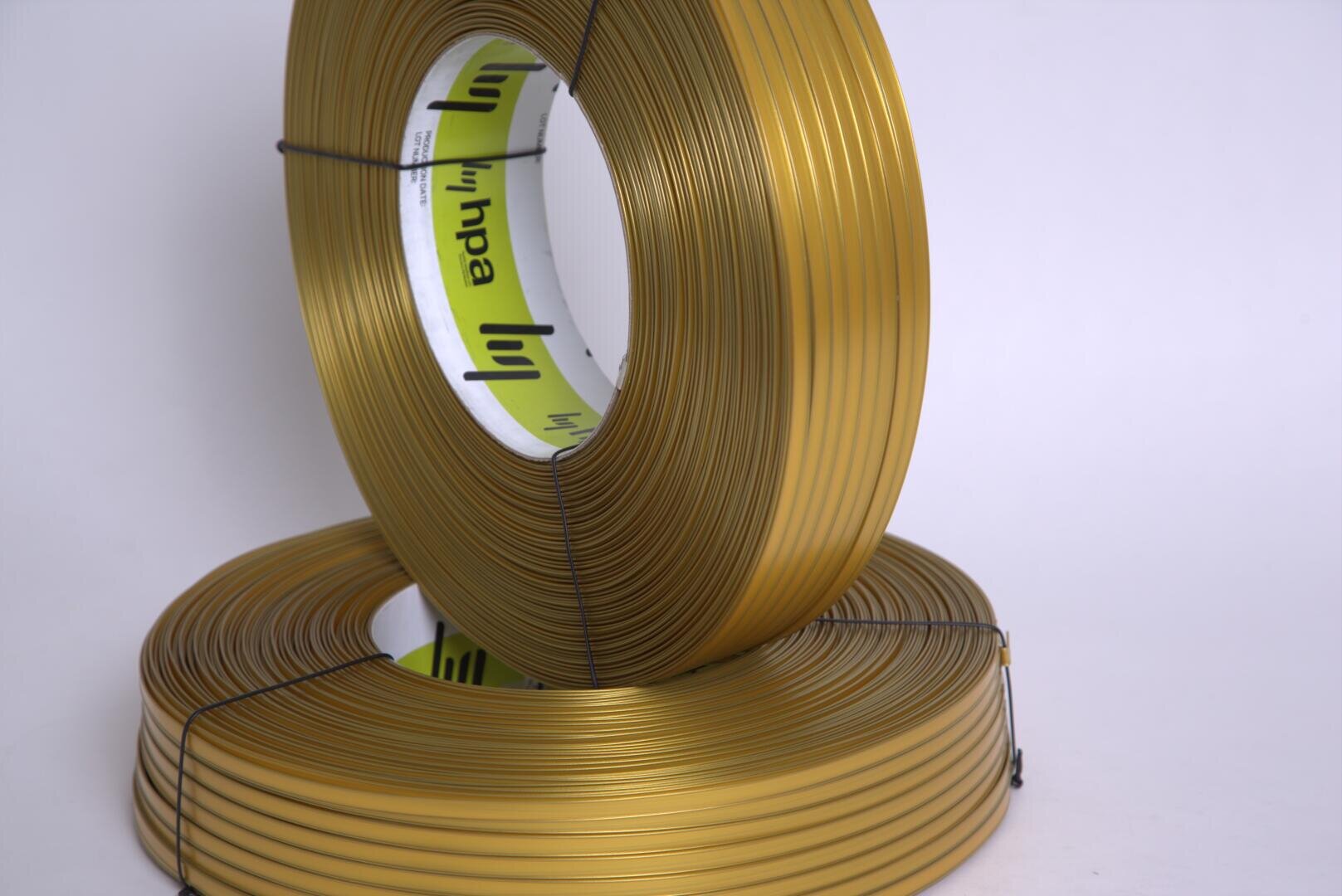 Two coils of gold-colored wire, one standing upright and the other lying flat, both bound with black ties; the inner label reads hpa with a green and white design on a plain light background.