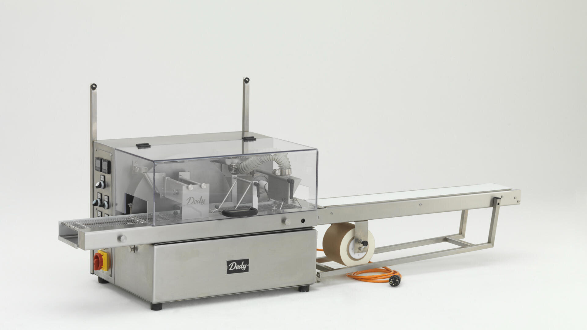 Eine industrielle Verpackungsmaschine aus Edelstahl mit einer transparenten Abdeckung, einem Förderband, einem Bedienfeld und einem orangefarbenen Stromkabel vor einem weißen Hintergrund.