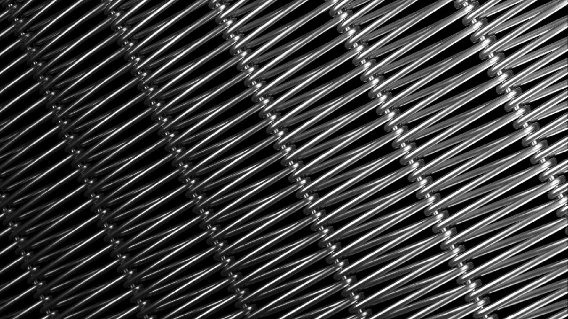 Close-up of diagonally aligned, tightly woven metal wires forming a repetitive geometric pattern, with highlights and shadows creating a strong sense of texture and depth.