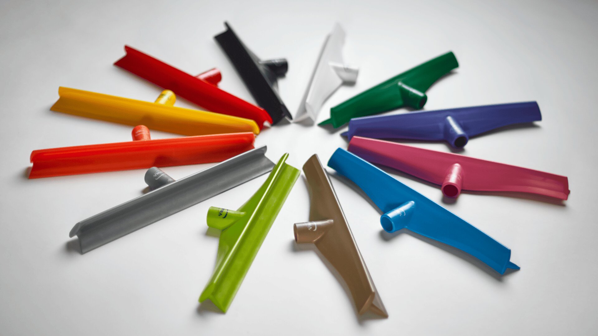 Colorful plastic tube cutter tools arranged in a circle on a white surface, with each cutter pointing outward like the spokes of a wheel.