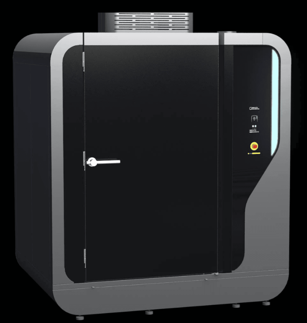 A large, modern industrial machine with a black door, metallic frame, control panel, emergency stop button, and a ventilation unit on top, standing against a black background.