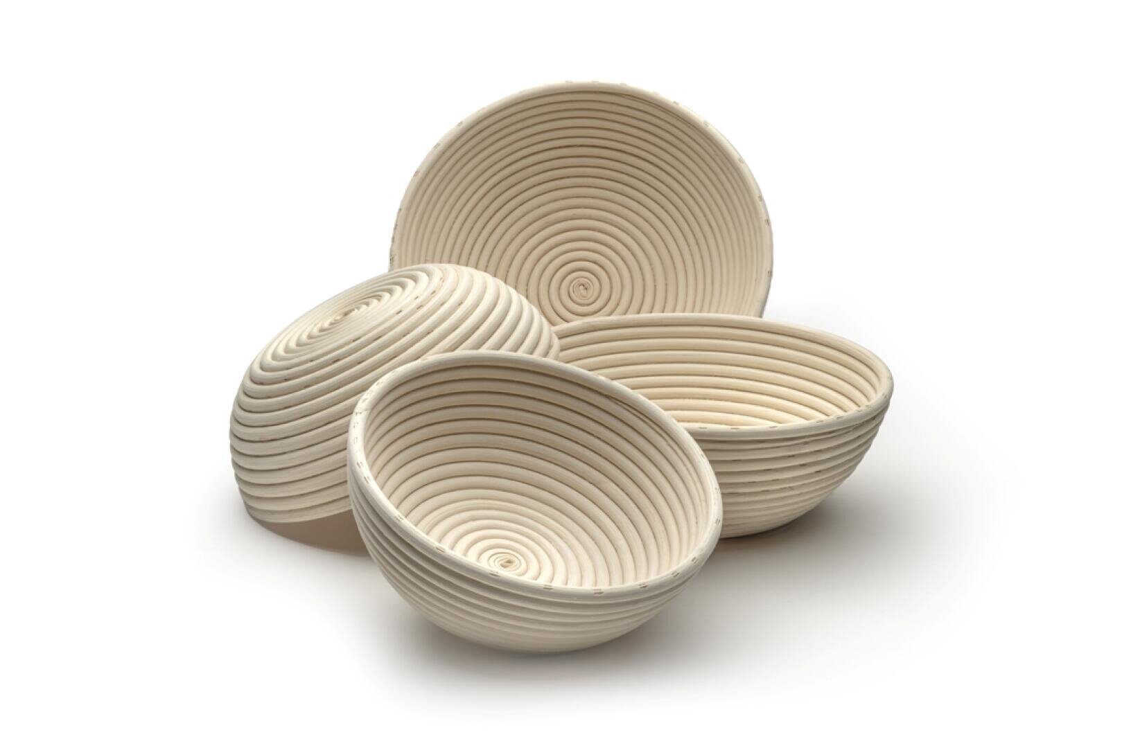 Vier runde, gewundene, helle Gärkörbe, auch Bannetons genannt, sind auf einem weißen Hintergrund angeordnet. Die Körbe haben ein spiralförmiges Muster im Inneren.