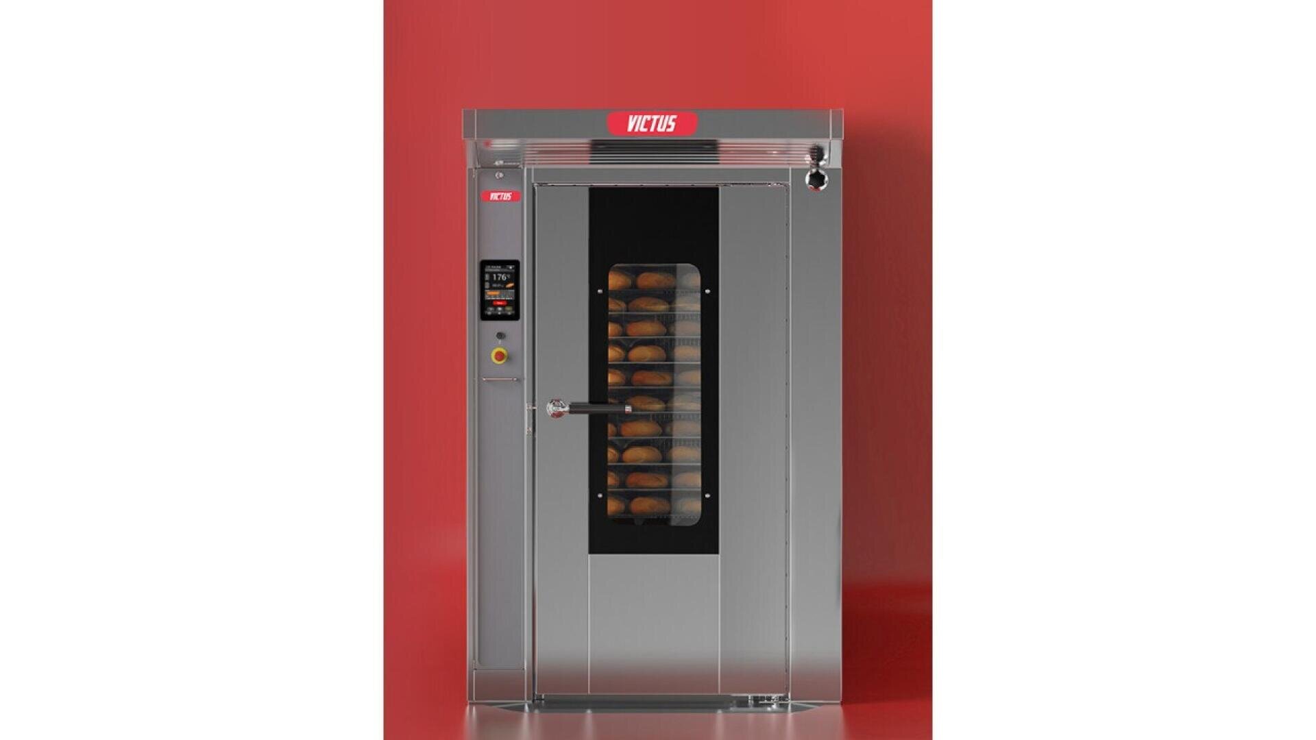 Ein großer kommerzieller Backofen aus rostfreiem Stahl mit einer Glastür, in deren Innerem sich Bleche mit gebackenen Broten befinden, vor einem soliden roten Hintergrund. Auf der linken Seite des Ofens befindet sich ein Bedienfeld.