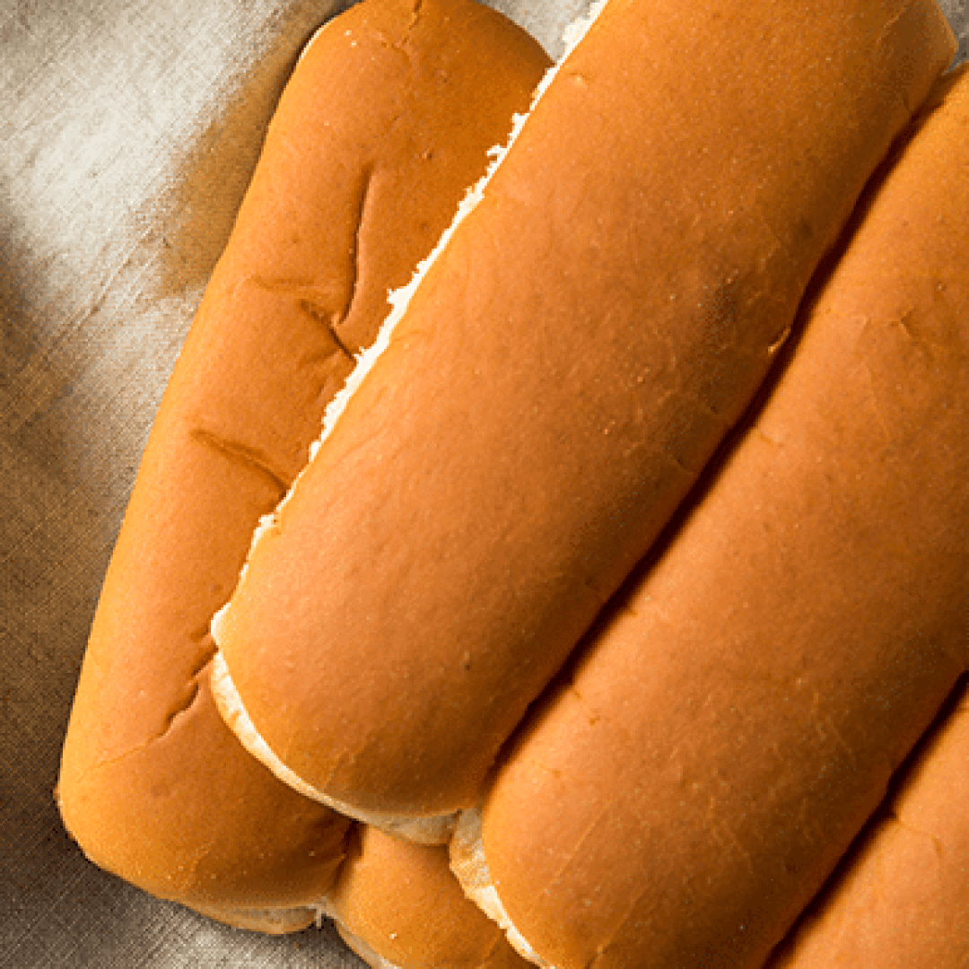 A close-up of three plain hot dog buns placed side by side on a textured surface.