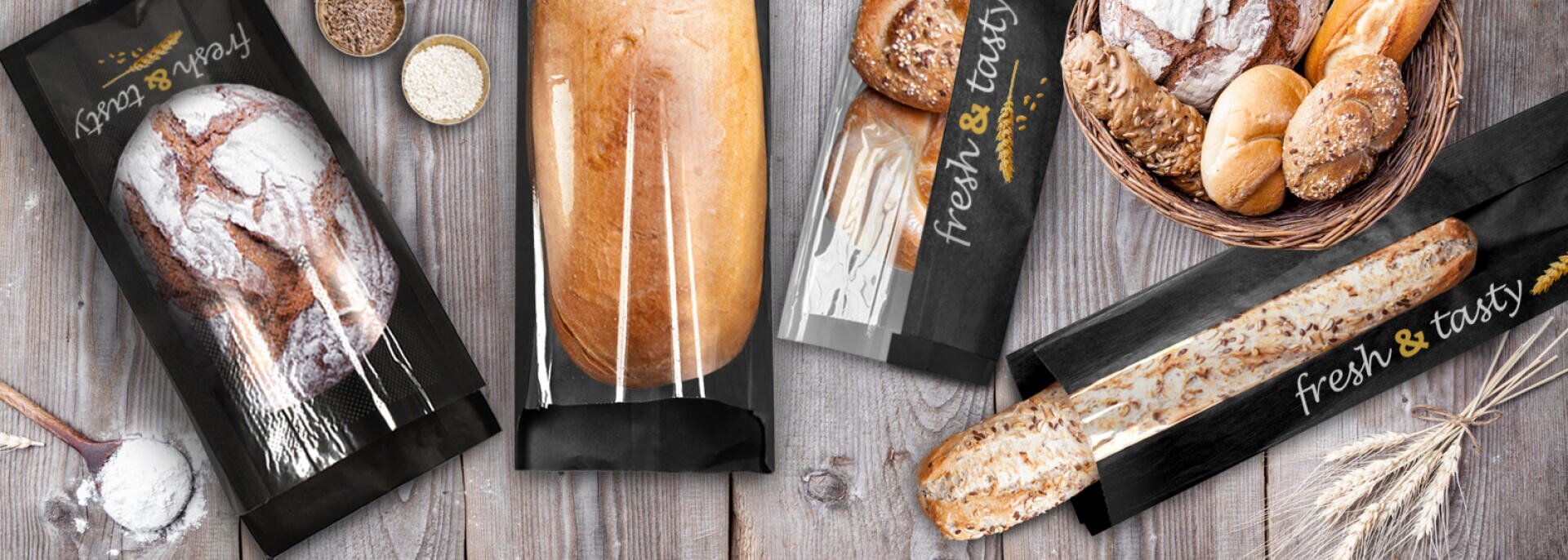 Verschiedene Brotsorten, darunter ein Laib, ein Baguette und Brötchen in einem Korb, werden auf einer rustikalen Holzfläche mit Weizen, Mehl und Samen präsentiert. Einige Brotsorten sind mit dem Etikett "frisch & lecker" verpackt.