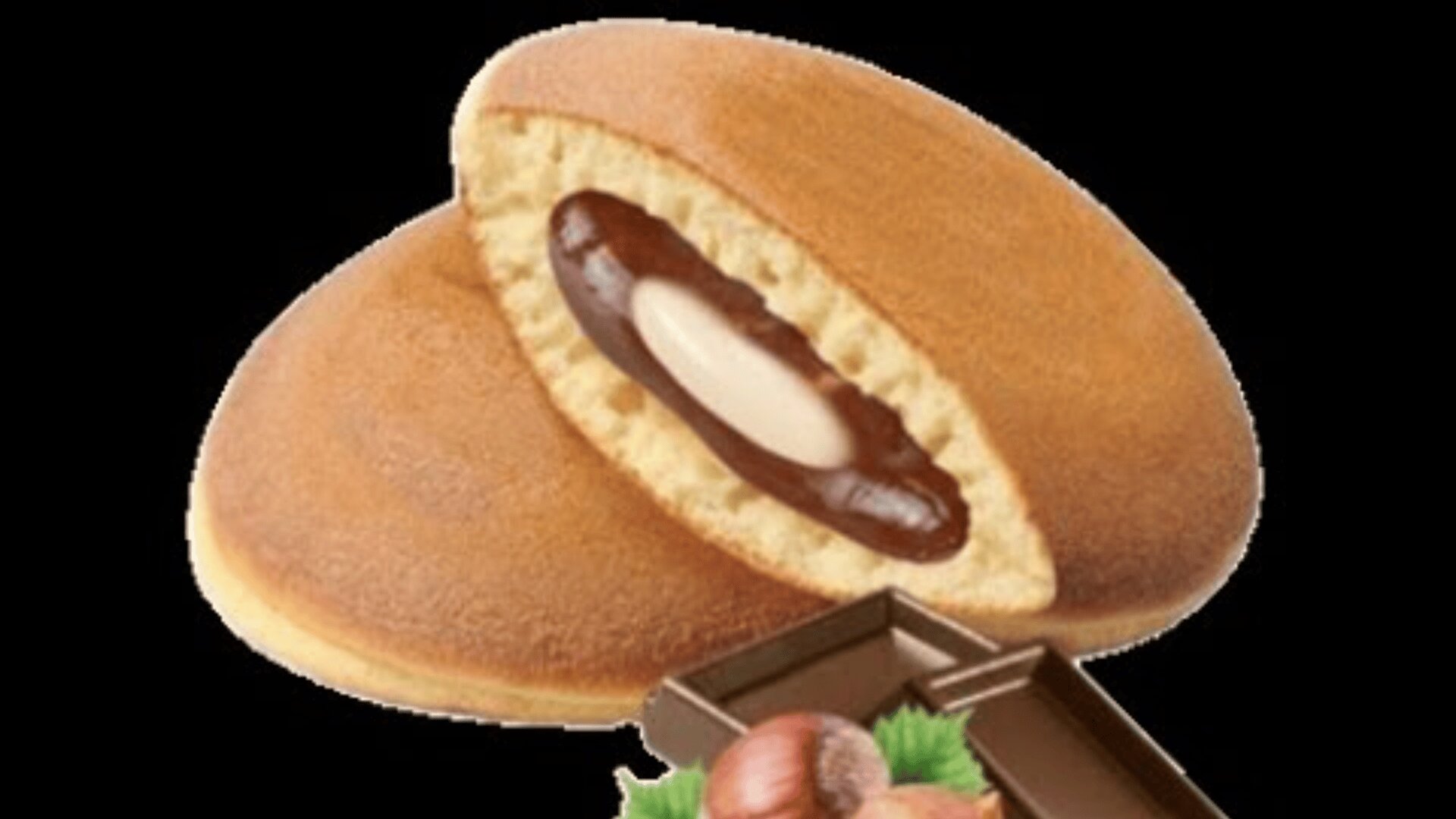 A pair of round, golden-brown pastries with one cut open to reveal a creamy white and chocolate filling, placed next to pieces of chocolate and hazelnuts on a black background.