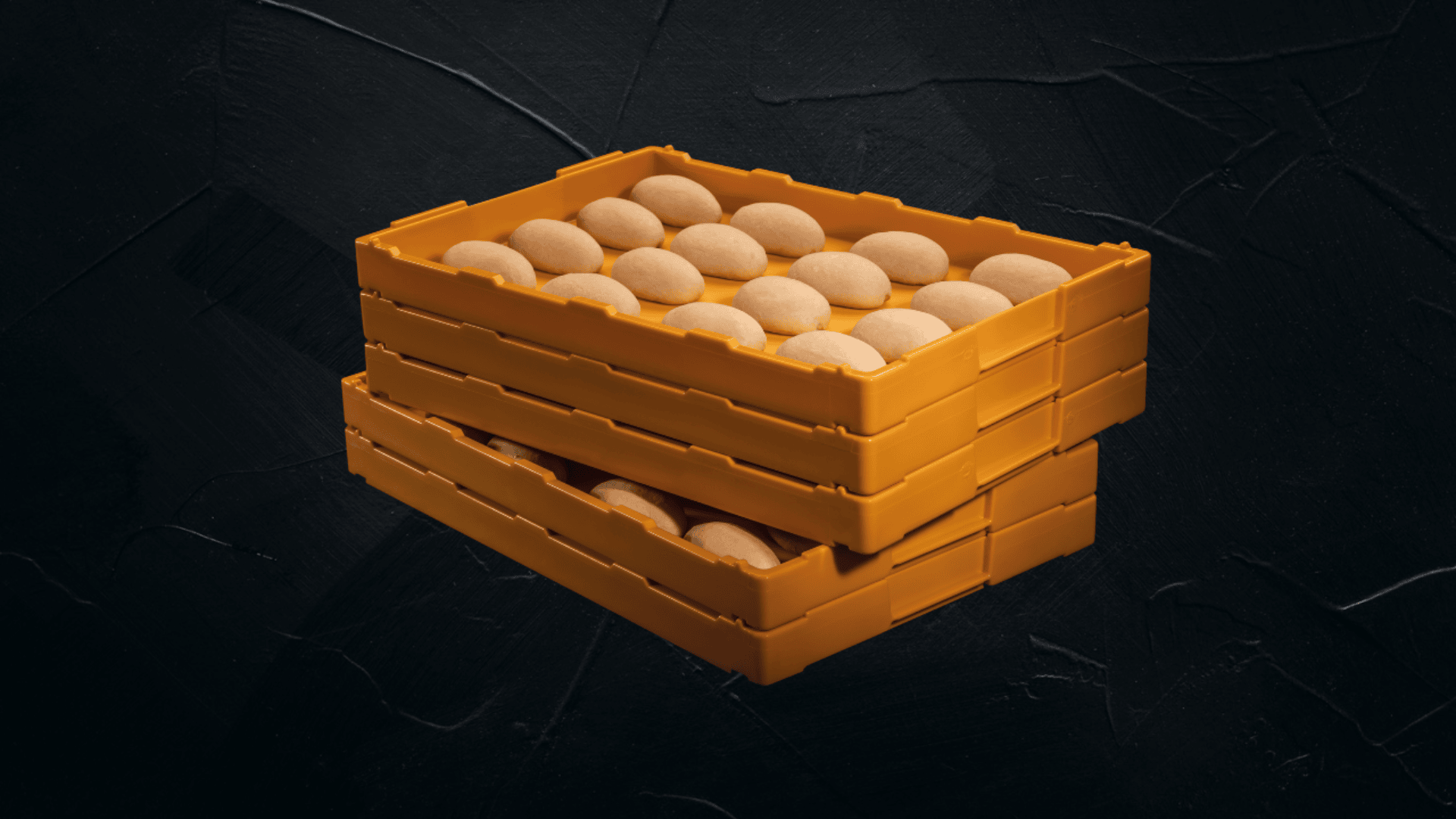 Drei gestapelte orangefarbene Plastikkisten, gefüllt mit gleichmäßig angeordneten braunen Eiern, vor einem dunkel strukturierten Hintergrund.