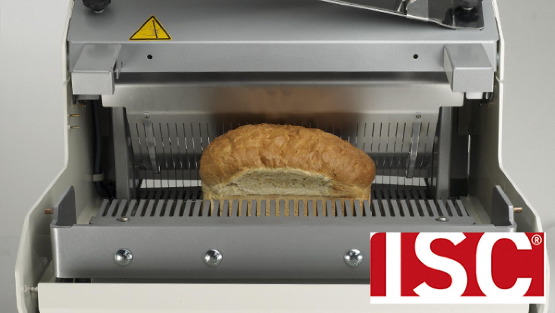 A loaf of bread is being sliced in an industrial bread slicer. The ISC logo is visible in the bottom right corner of the image.