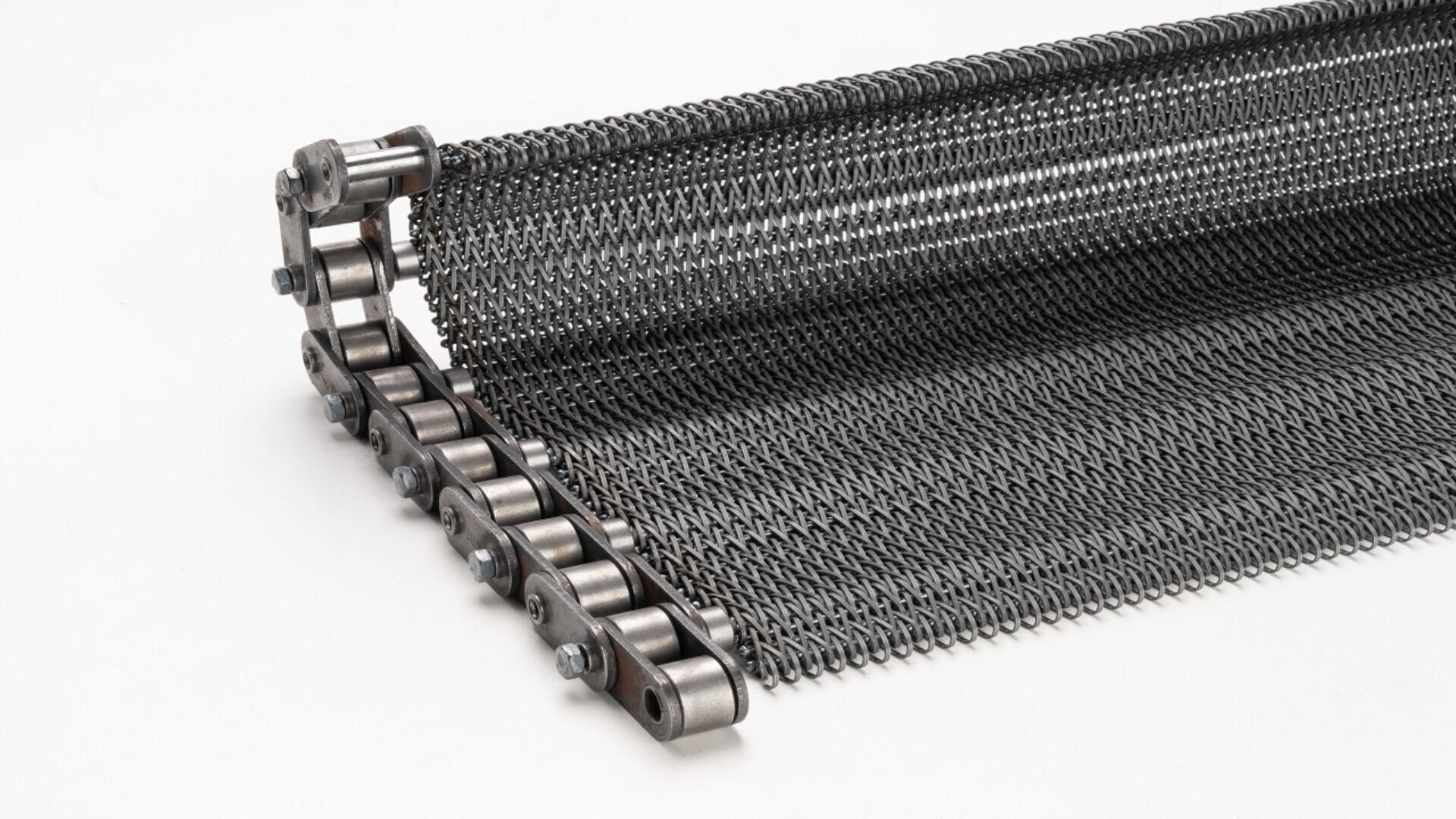 Close-up of a metal conveyor belt with linked wire mesh and a roller chain on one edge, designed for industrial use, against a white background.