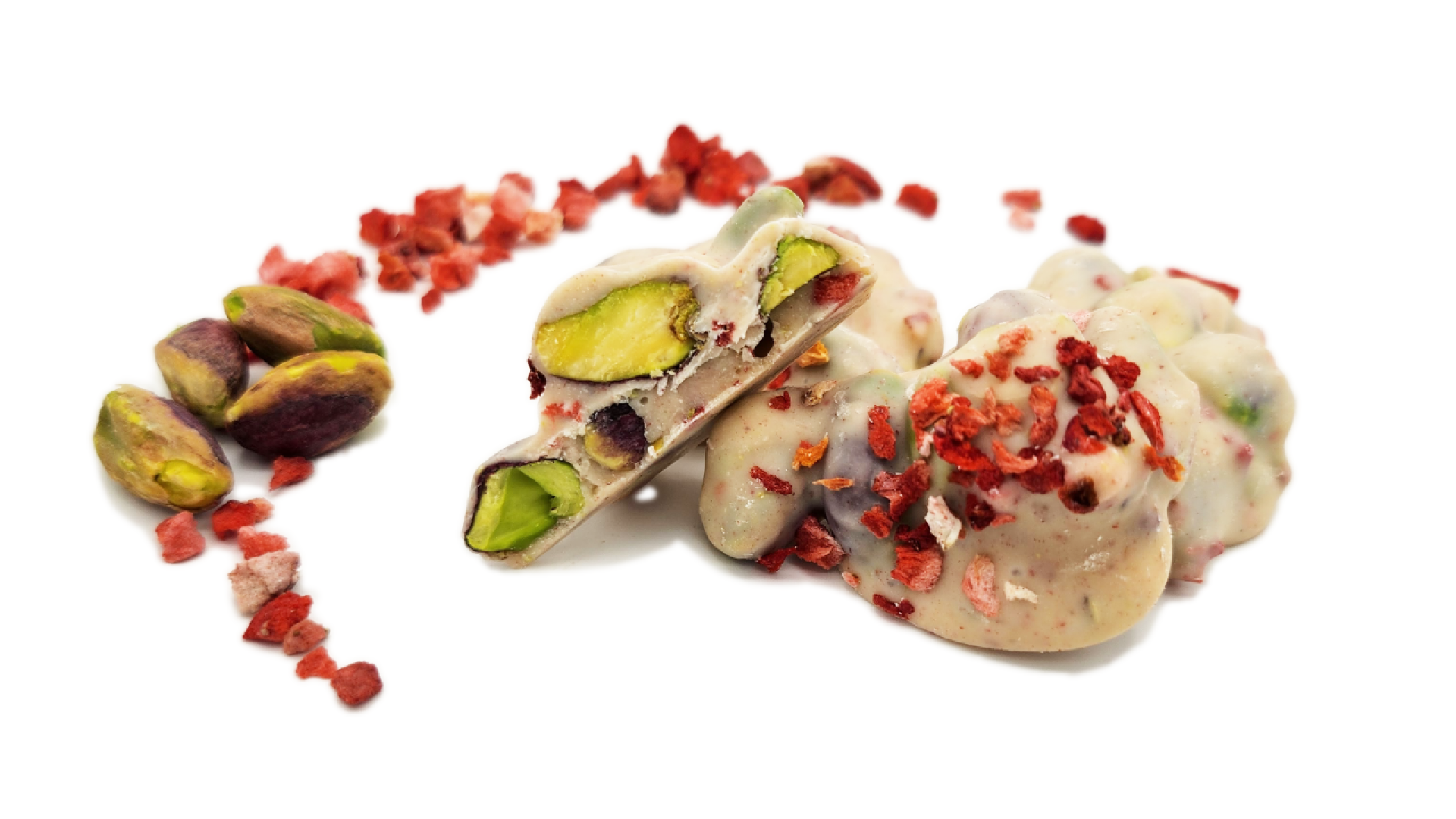 White chocolate clusters with whole pistachios and dried strawberry pieces, arranged on a white background. Some loose pistachios and bits of dried strawberry are scattered beside the clusters.