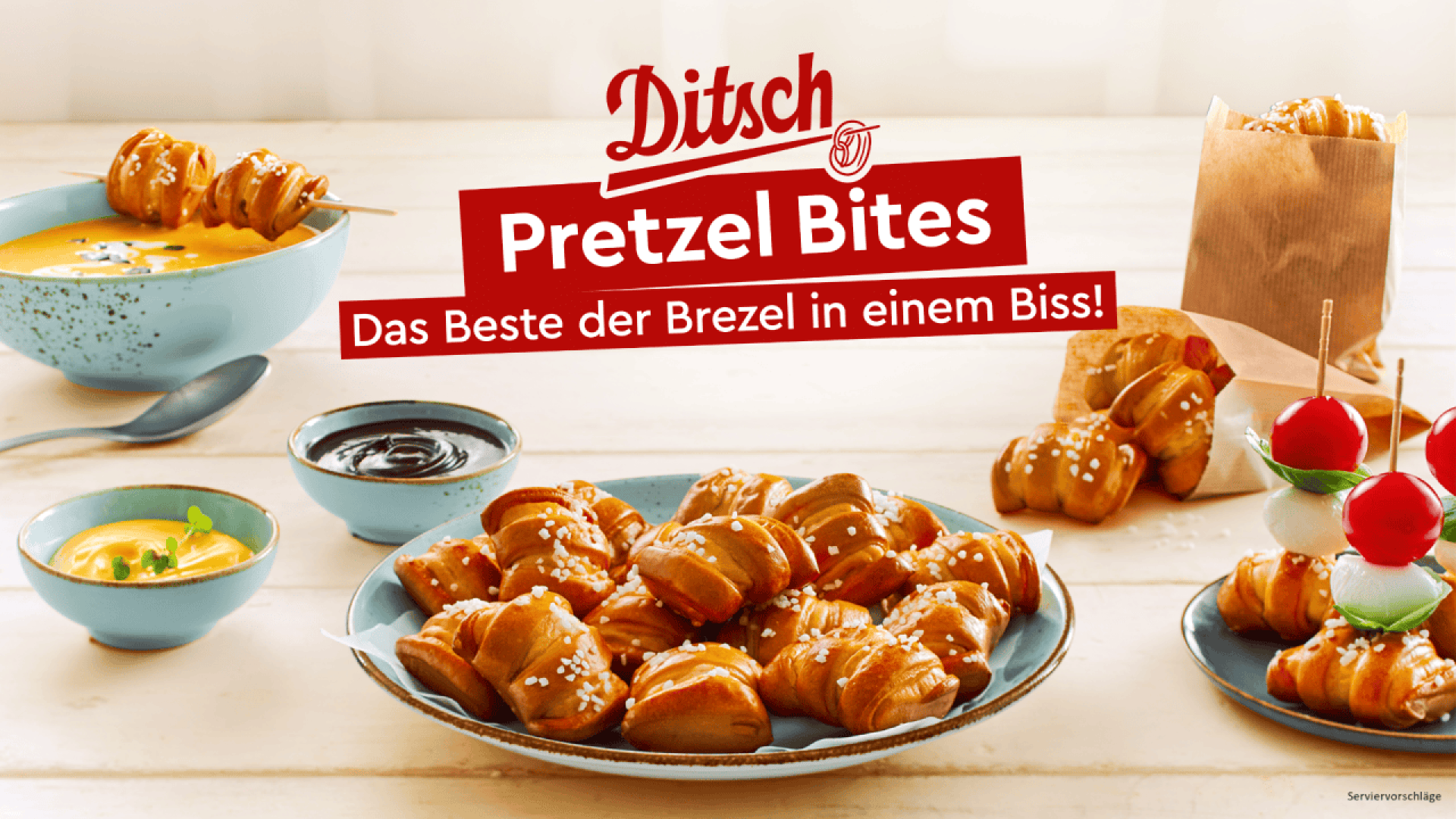 Assorted pretzel bites topped with salt are served in bowls and a paper bag, accompanied by cheese and chocolate dips, and skewered with tomatoes and mozzarella. The text reads: “Ditsch Pretzel Bites. Das Beste der Brezel in einem Biss!”.