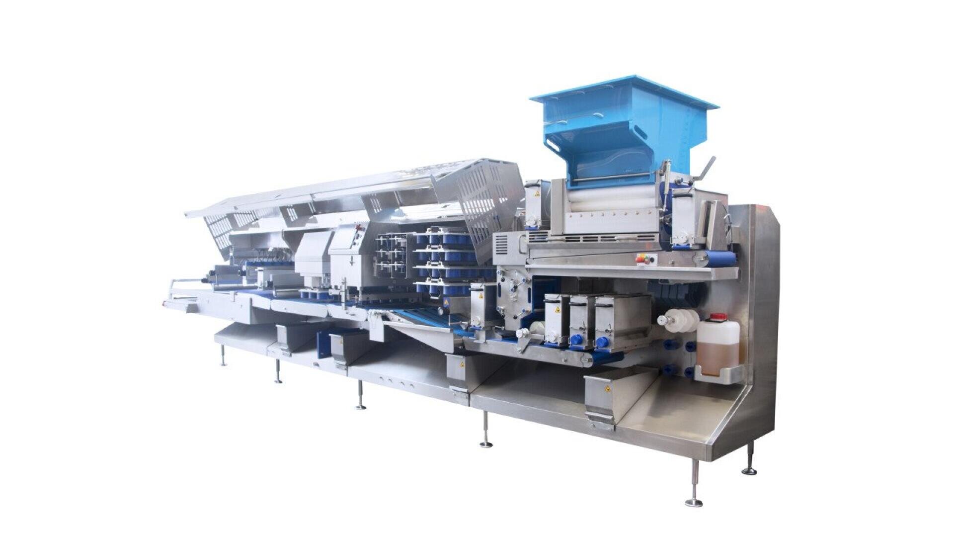 A large, stainless steel industrial food processing machine with multiple compartments, rollers, and a blue hopper on top, designed for automated production in a clean, sterile environment.