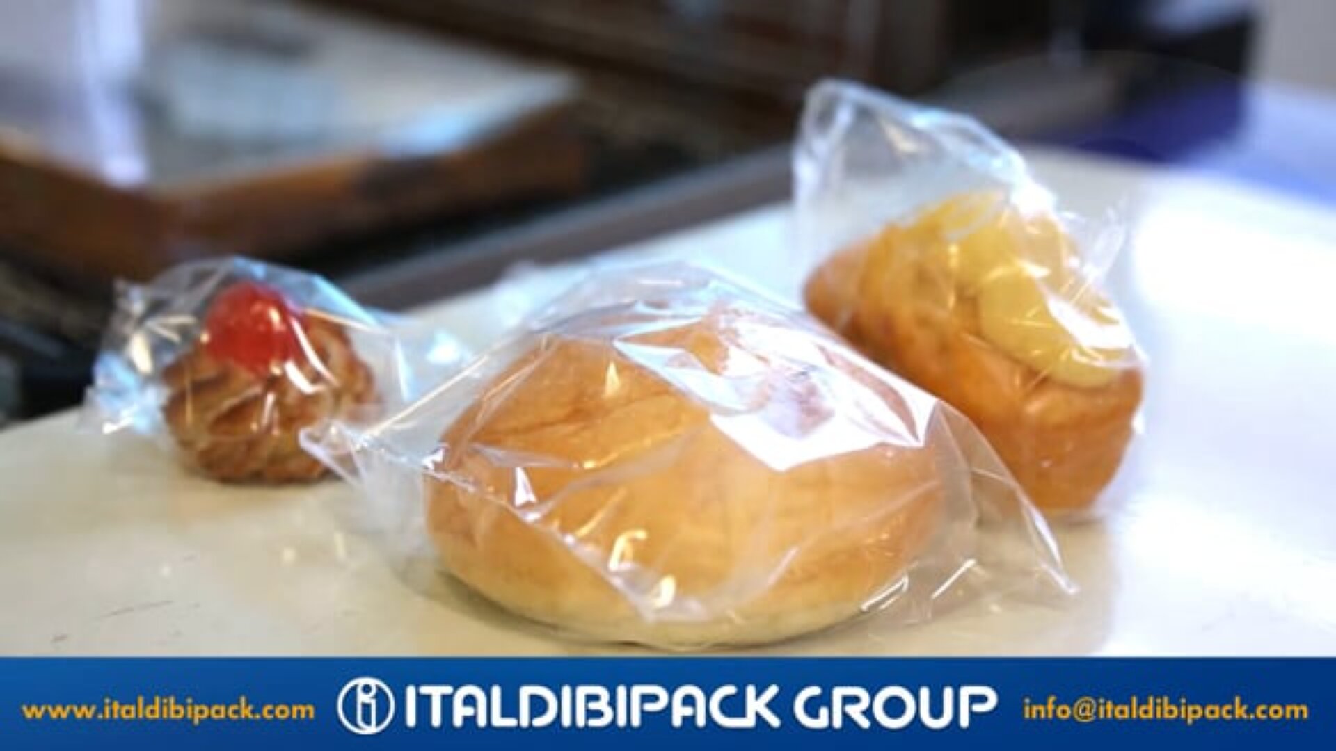 Three assorted pastries individually wrapped in clear plastic are displayed on a white surface. The image features the Italdibipack Group logo and contact information at the bottom.