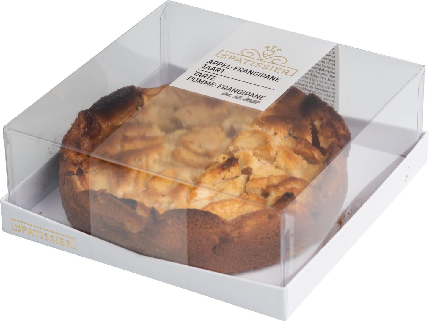 A round apple frangipane tart in a white box with a clear plastic lid, partially revealing the golden-brown tart inside. The box has a label with product information.