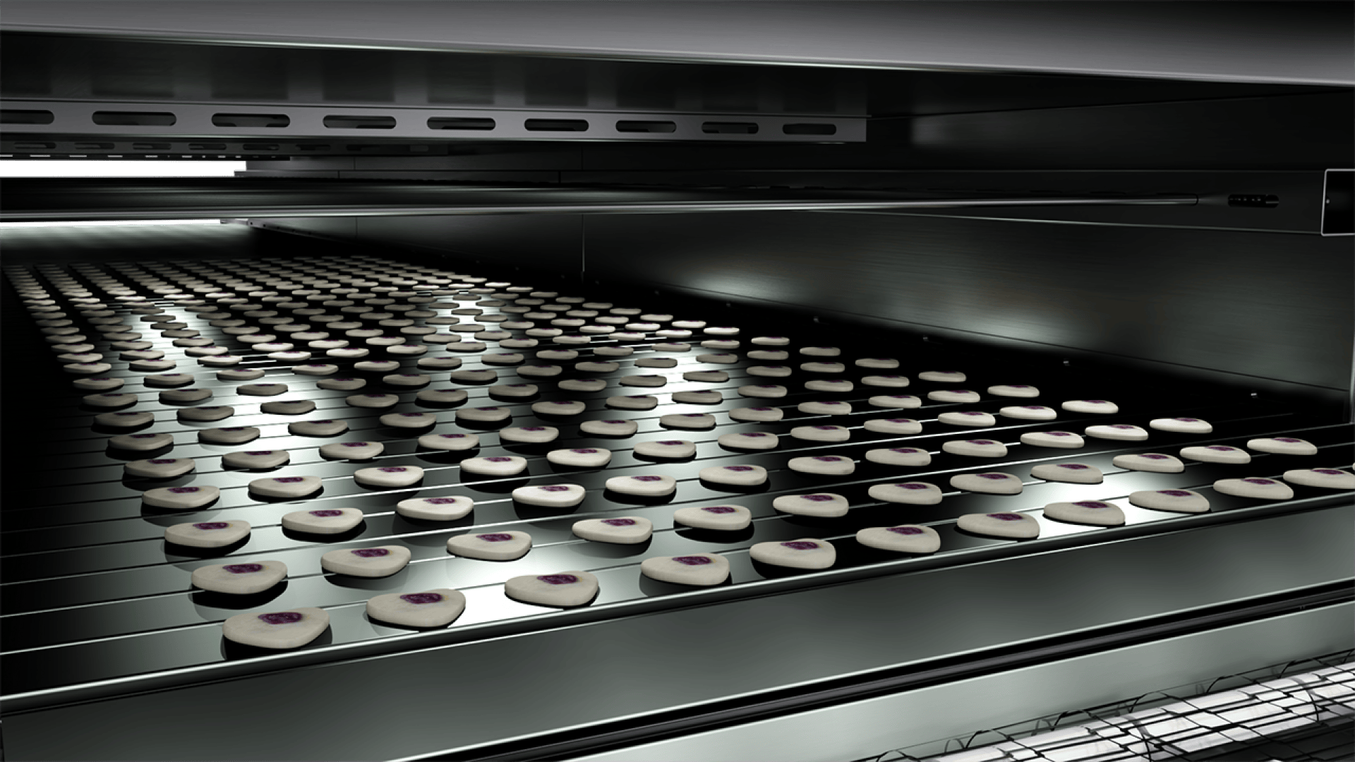 Rows of small round cookies with a purple dot in the center move along a conveyor belt inside a large industrial oven, suggesting a high-volume automated baking process.