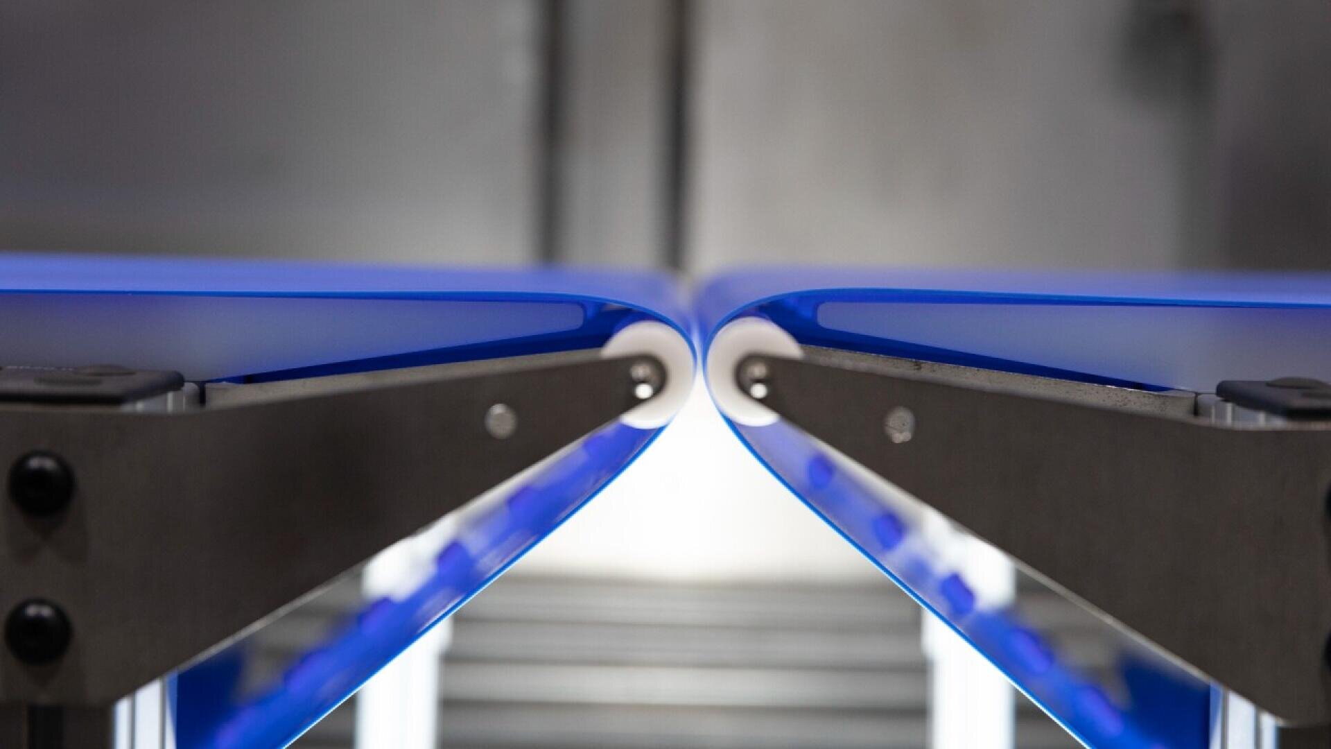 Nahaufnahme von zwei gegenüberliegenden blauen Förderbändern mit einem kleinen Abstand zwischen ihnen. Die glatten Kanten und der Metallrahmen in einer industriellen Umgebung sind zu sehen.