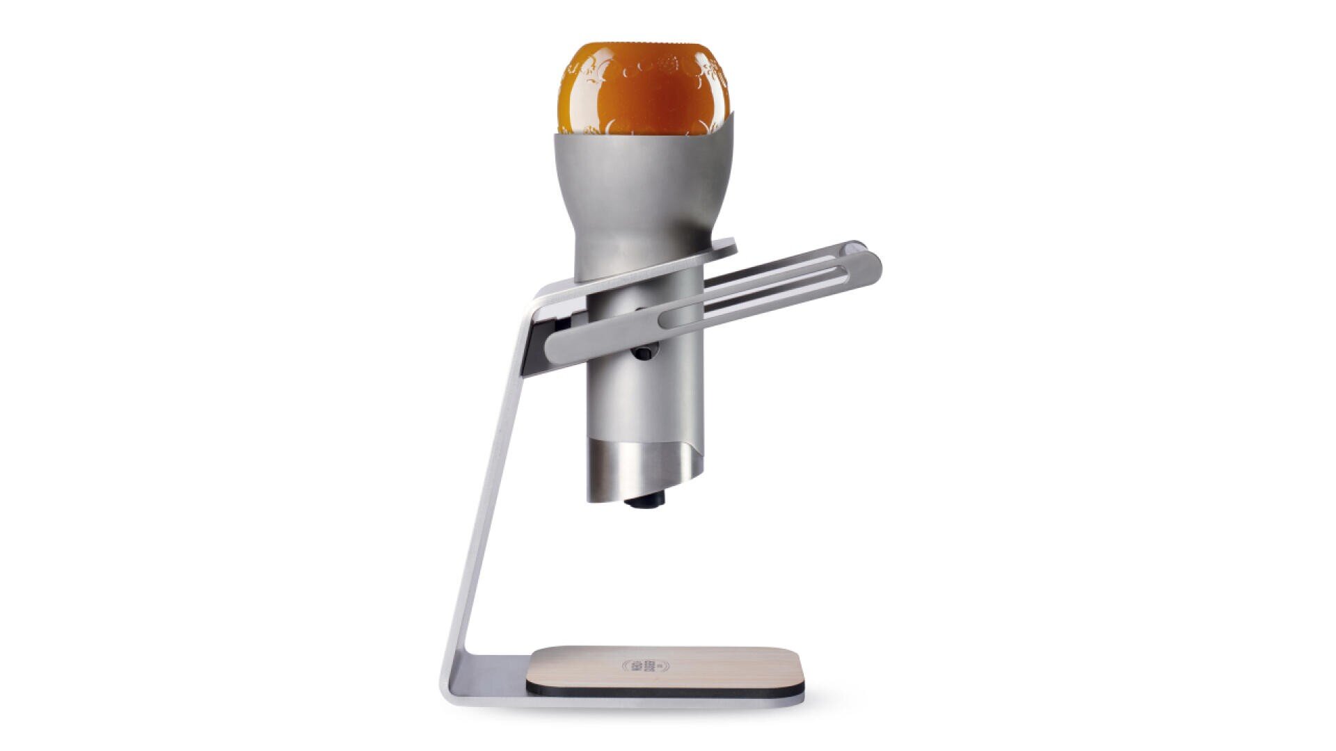 Ein modernes, silbernes Gerät hält eine auf dem Kopf stehende Bierflasche über einer hölzernen Plattform, die zum mühelosen Einschenken oder Servieren von Bier dient.