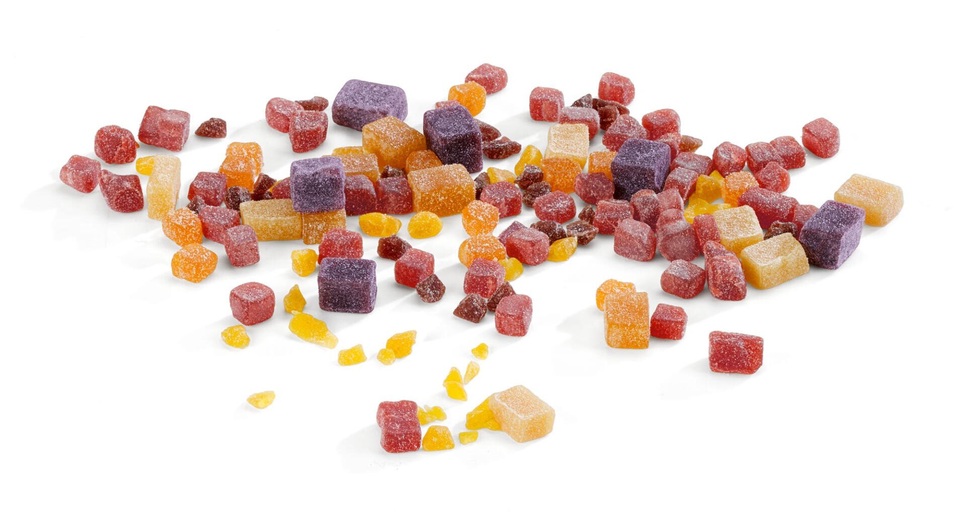 Eine Vielzahl von bunten, kleinen, mit Zucker überzogenen Gummibonbonwürfeln, die auf einer weißen Oberfläche verstreut sind. Die Bonbons gibt es in den Farben Rot, Orange, Gelb und Lila.