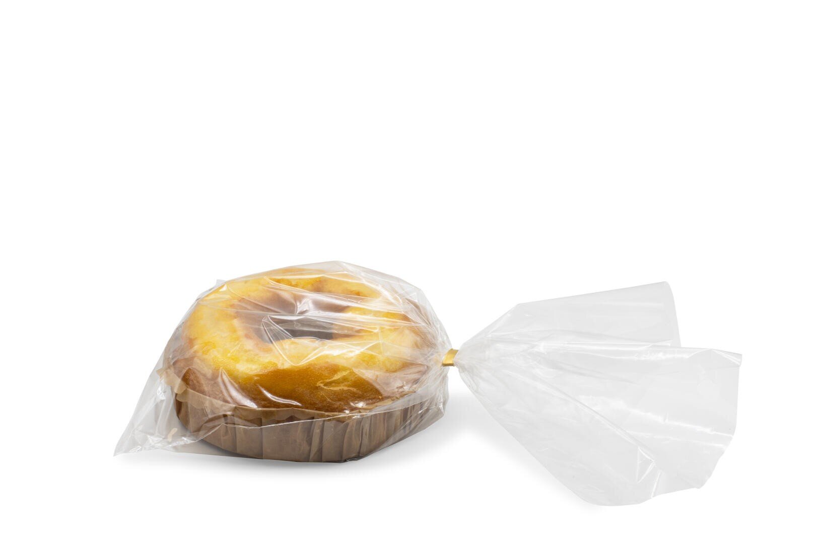 Ein runder Laib gelben Kuchens oder Brots, in durchsichtige Plastikfolie eingewickelt, an einem Ende zusammengebunden und auf einem weißen Hintergrund platziert.