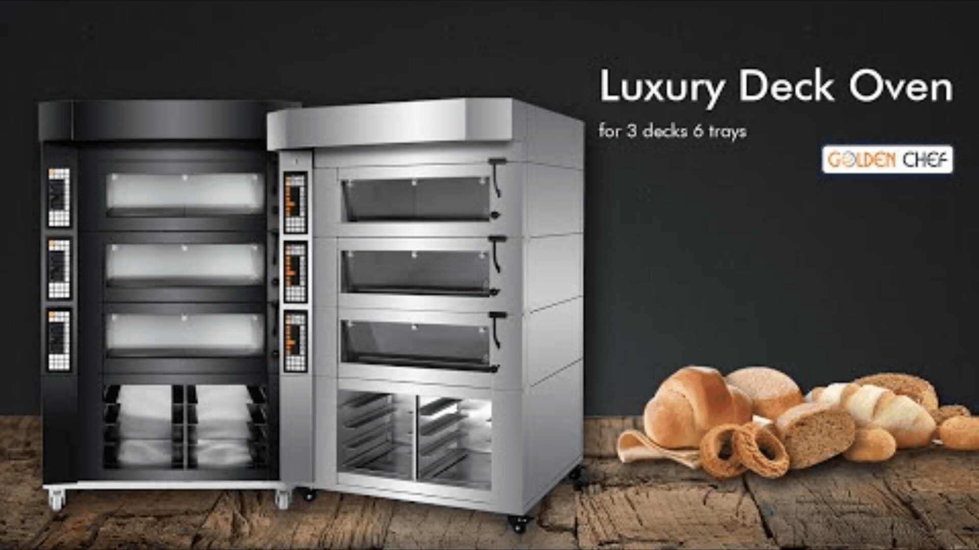 Two large, silver luxury deck ovens with glass doors stand side by side on a wooden floor. Various types of bread and rolls are displayed in the foreground. Text reads Luxury Deck Oven for 3 decks 6 trays – GOLDEN CHEF.