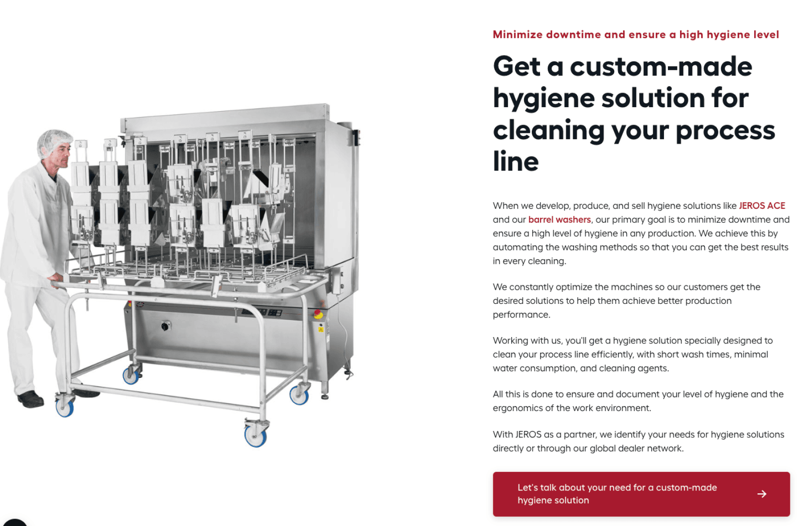 A person in white protective clothing stands next to a large stainless steel industrial machine with multiple nozzles, used for cleaning barrels or process equipment in a hygienic environment.