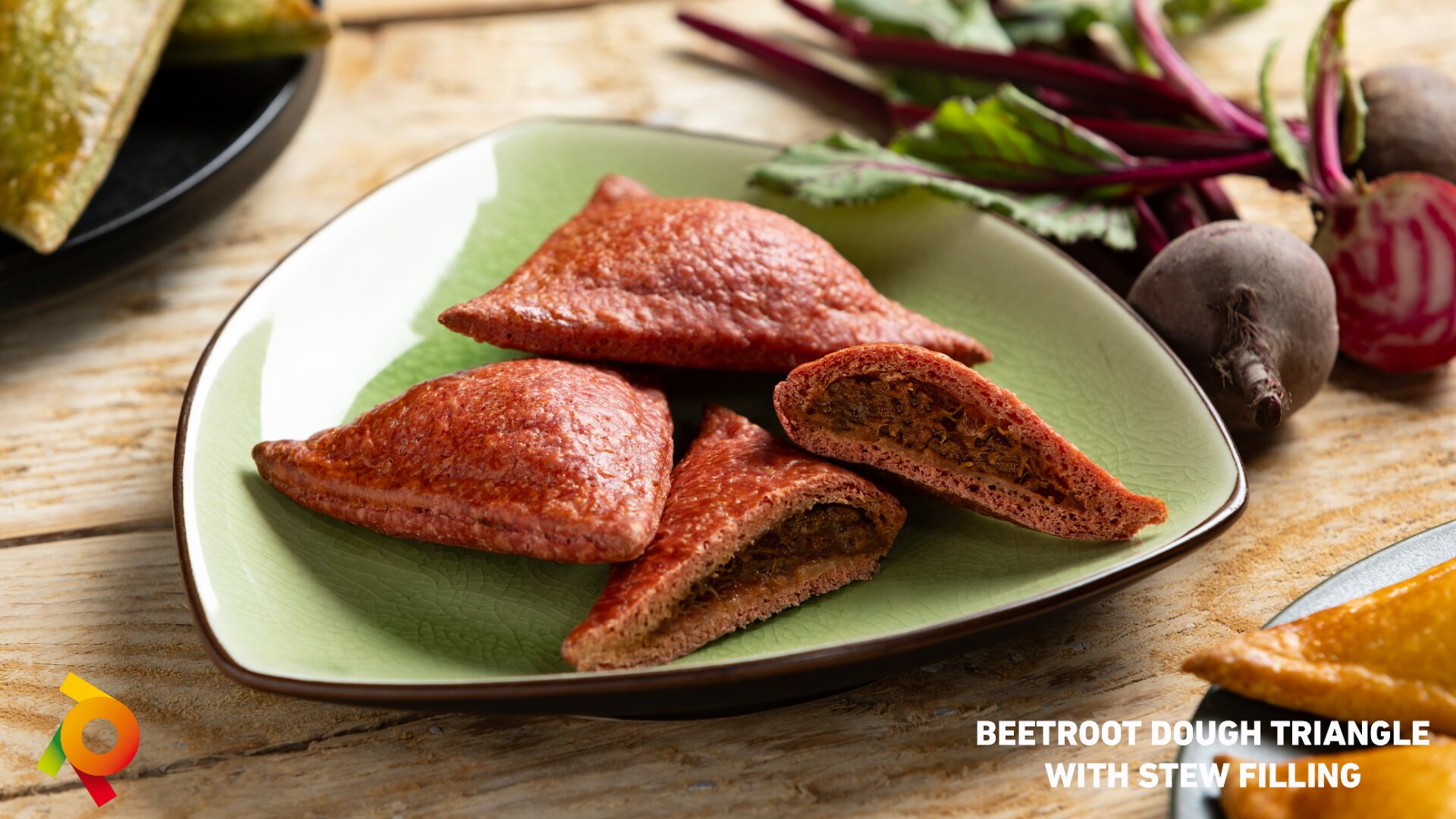 Three triangular pastries with reddish beetroot dough and stew filling are arranged on a green plate, with fresh beets in the background. Text reads: Beetroot dough triangle with stew filling.