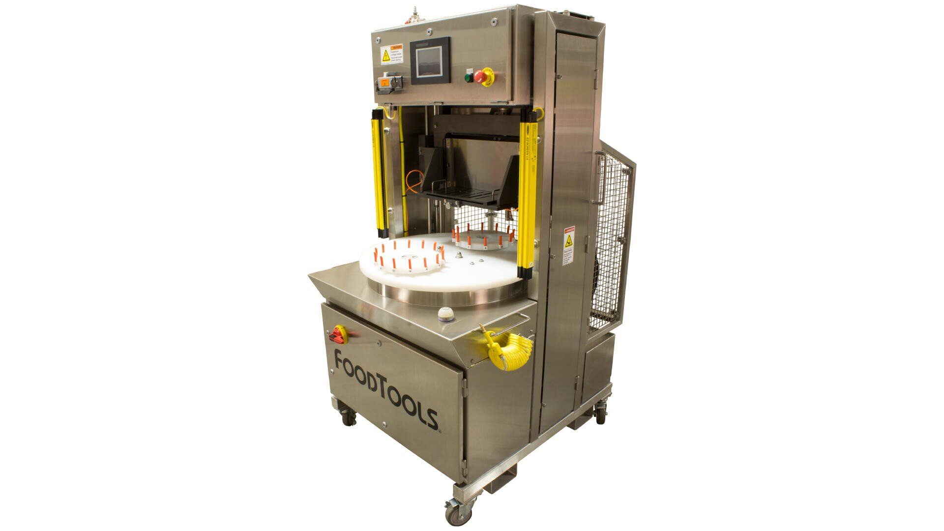 A stainless steel industrial food processing machine with a circular rotating platform, labeled FOODTOOLS, designed for automated slicing or cutting in food production. The machine has safety guards and control buttons.