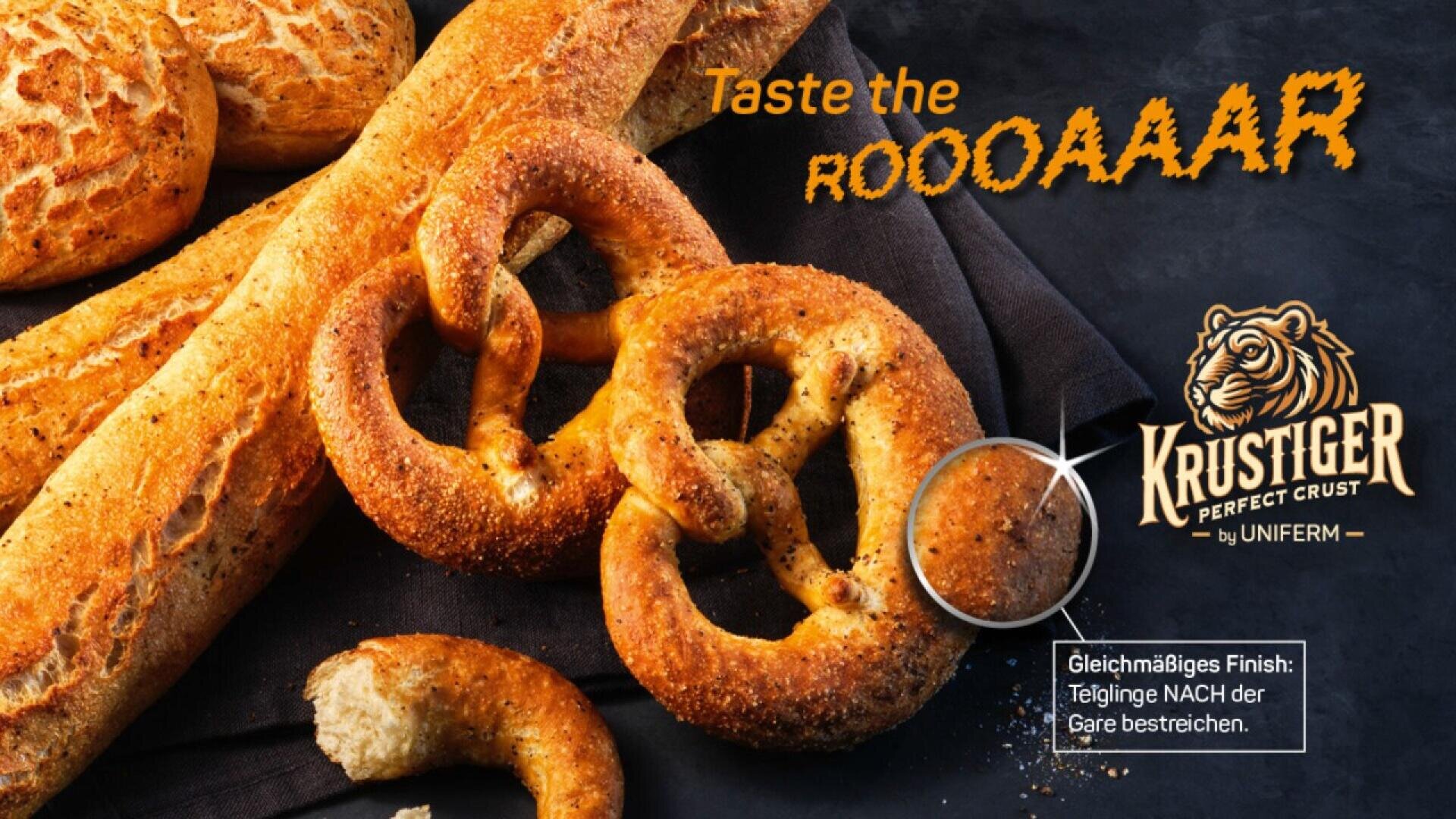 A close-up of assorted baked goods, including pretzels and baguettes, with the text Taste the ROOOAAAR and KRUSTIGER Perfect Crust by UNIFERM overlaid, plus a tiger logo and a baking instruction in German.